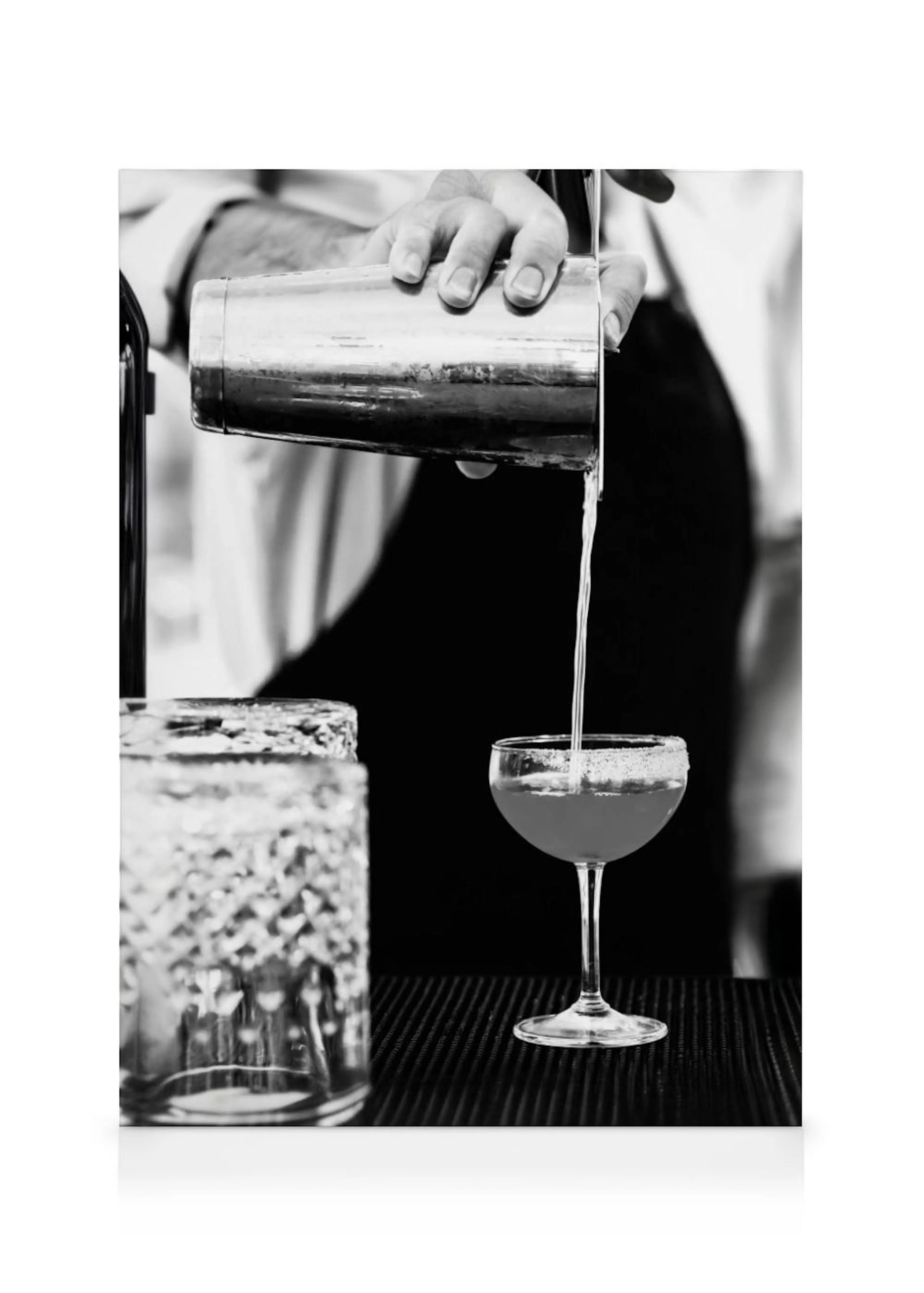 A black and white canvas of a bartender pouring a drink from a shaker into a glass.
