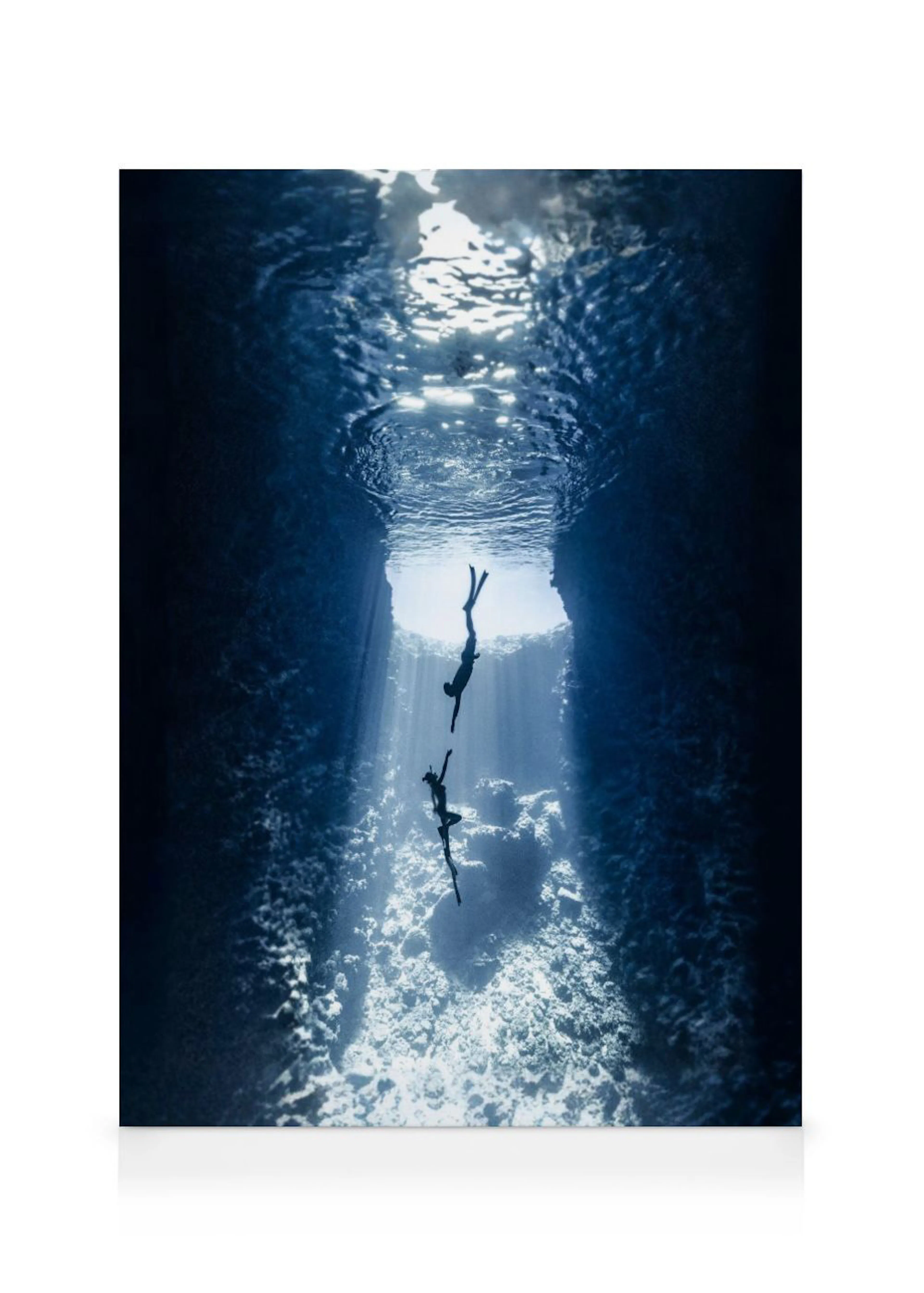 A canvas showing two free divers descending into a dark blue underwater cave with light rays from above.