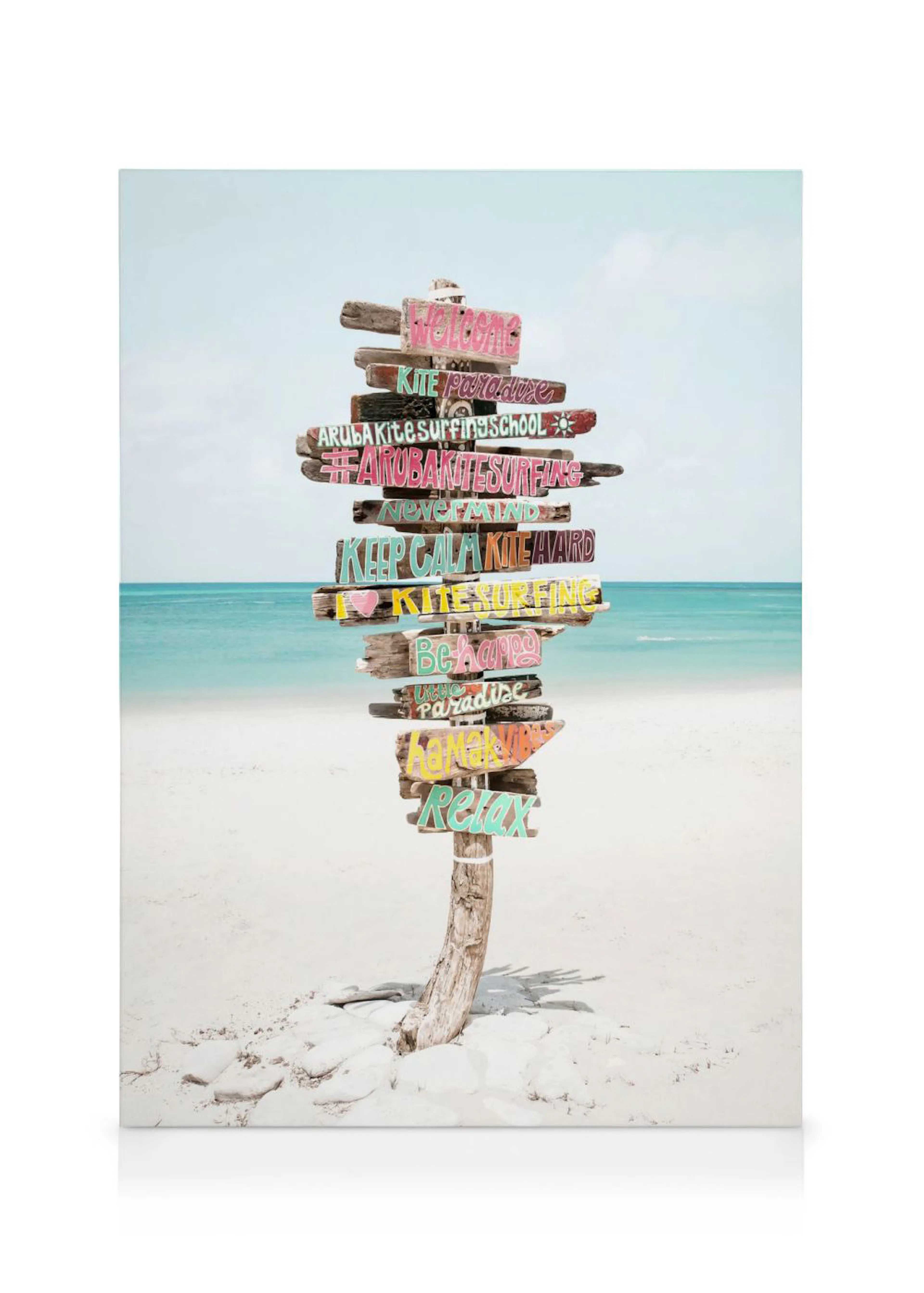 Lienzo de un poste con carteles de madera de colores en una playa tropical de arena blanca con el mar de fondo.