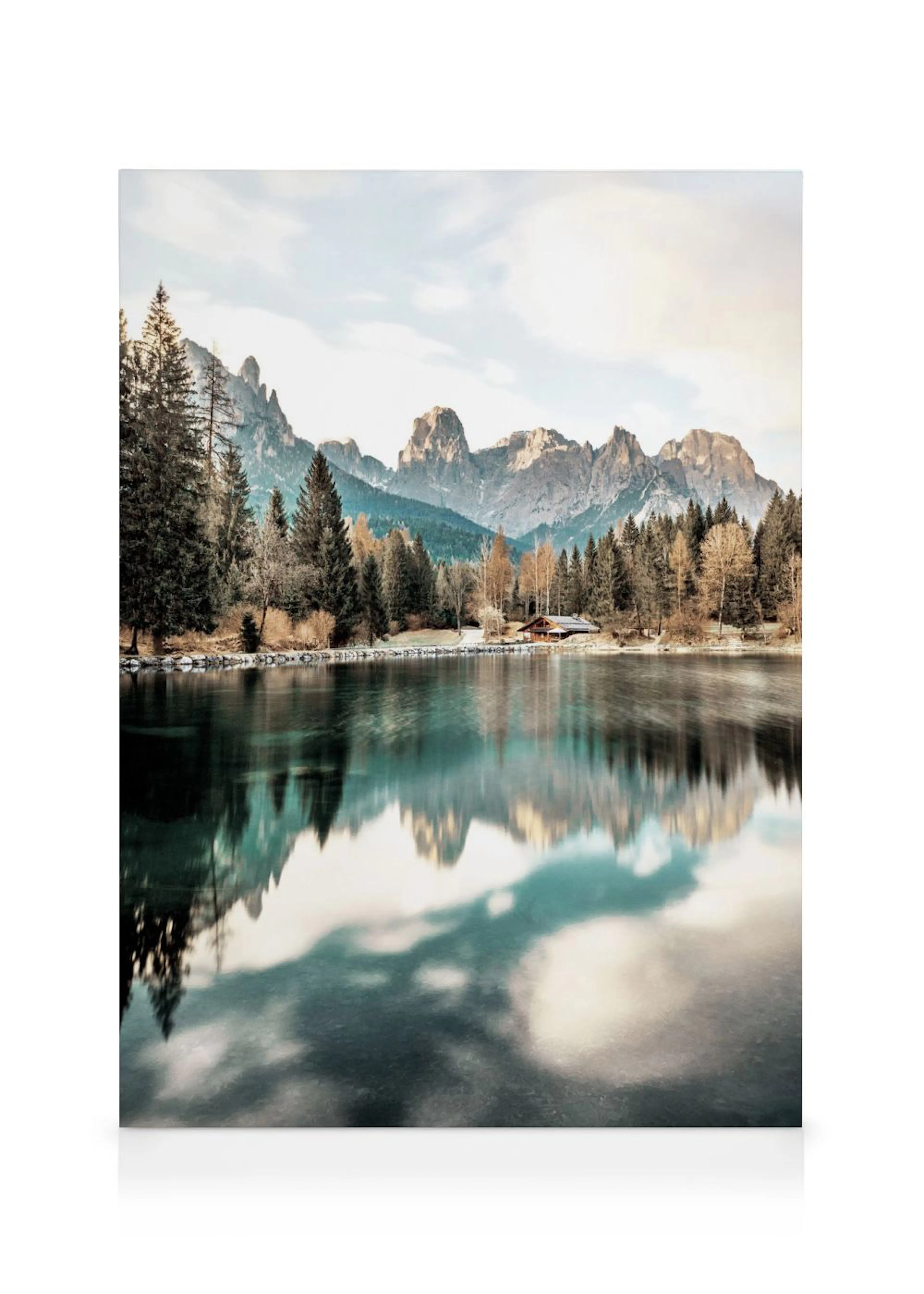 Leinwandbild eines Bergsees mit Fichtenwald und Holzhütte, die sich im ruhigen Wasser spiegeln.