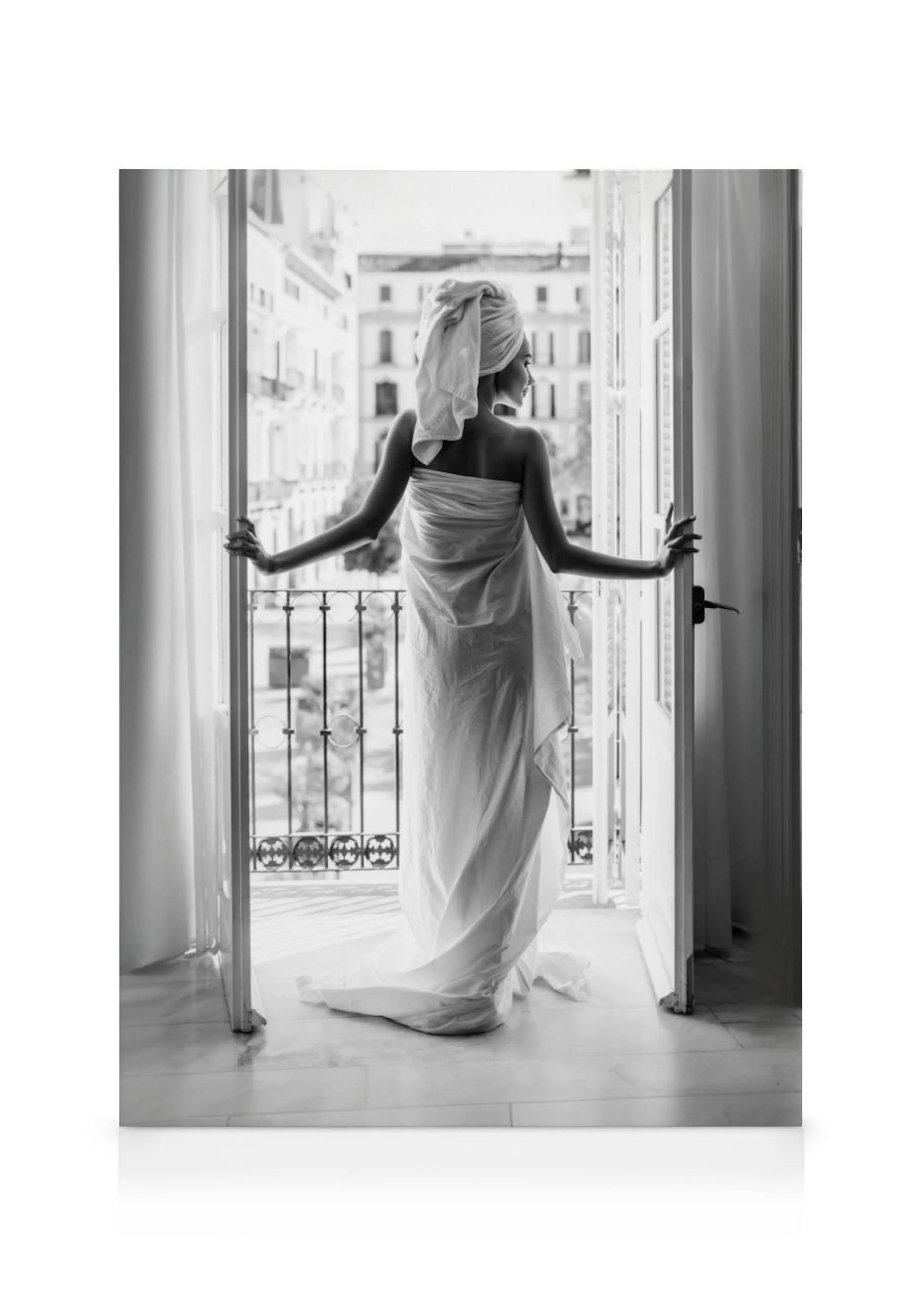 A black and white canvas of a woman wrapped in a towel looking out from a balcony over a city street.