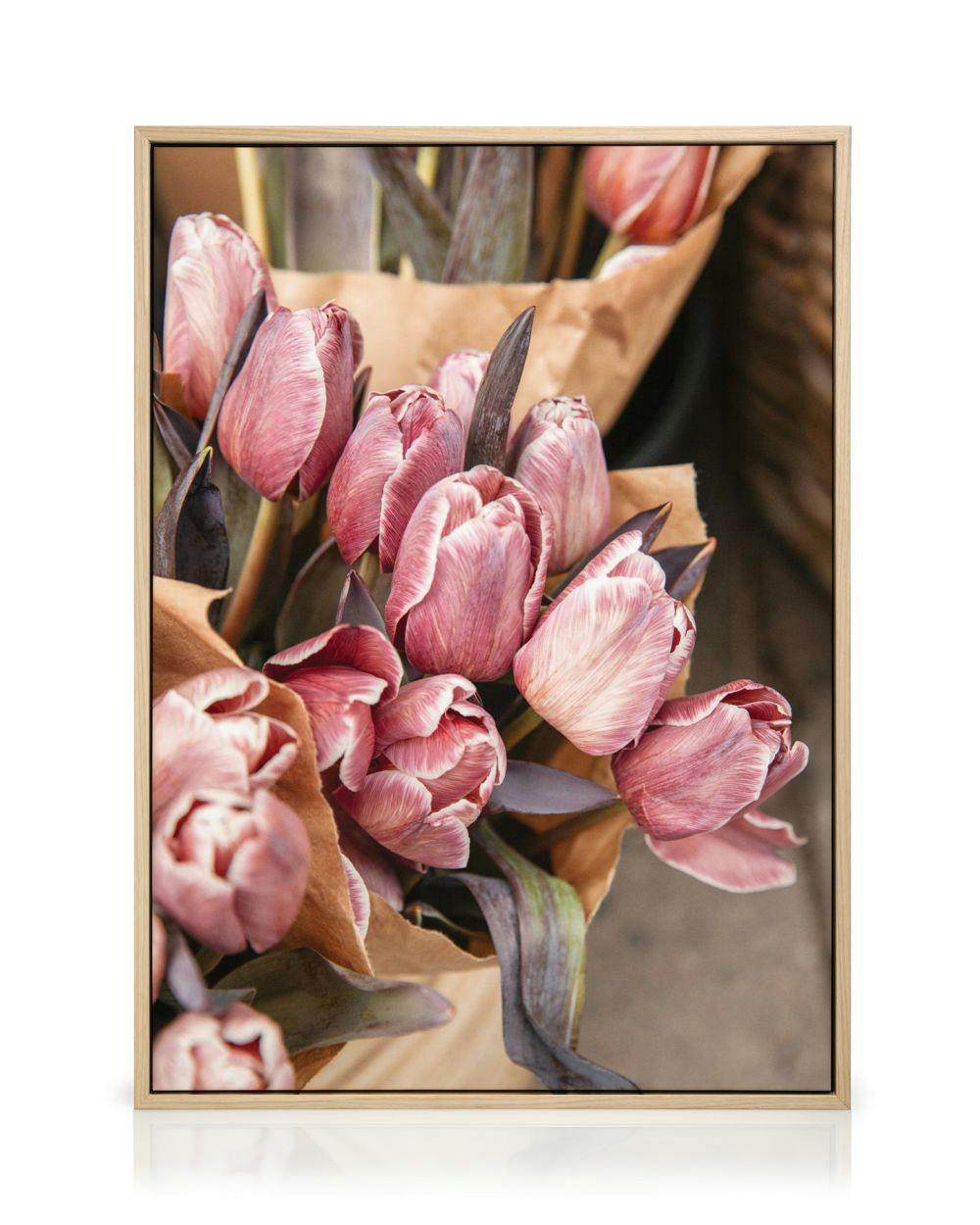 Canvas met een close-up van een boeket roze tulpen in bruin papier, met donkere stengels.