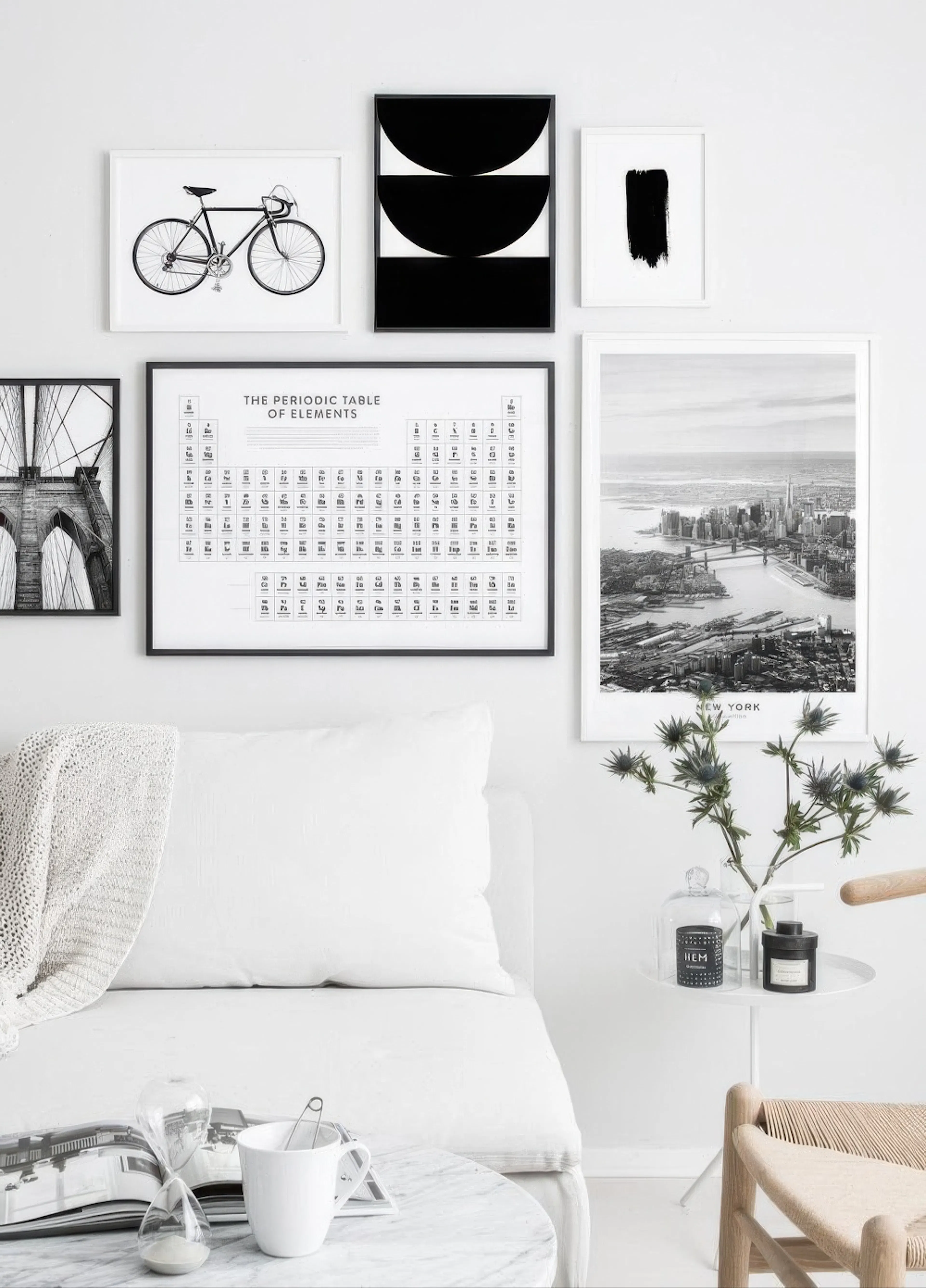 A gallery wall featuring a bicycle, abstract black shapes, a black brushstroke, the Periodic Table, and a NYC skyline poster, ab