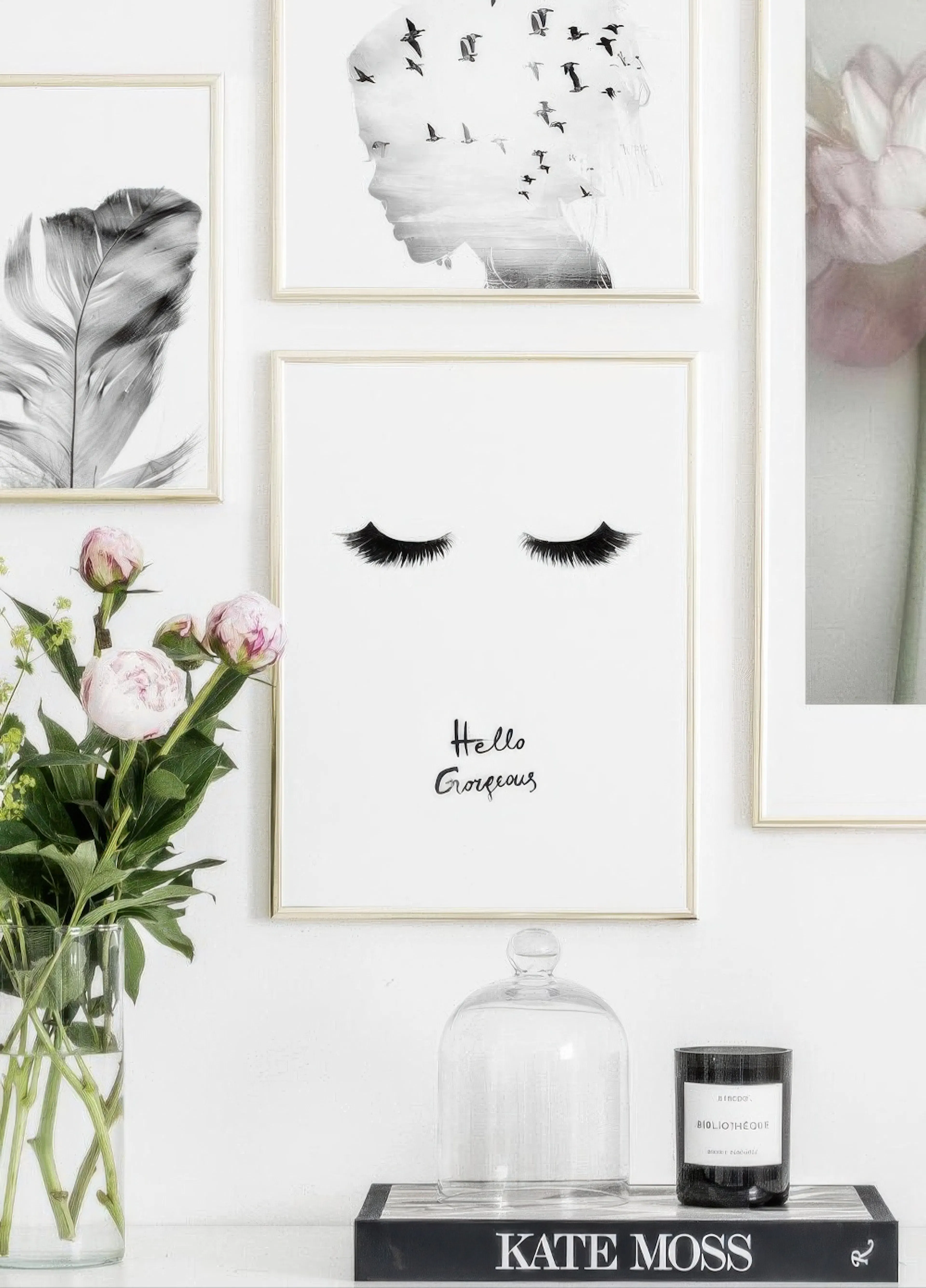 A poster of black eyelashes and Hello Gorgeous text, part of a gallery wall above a console table with flowers.
