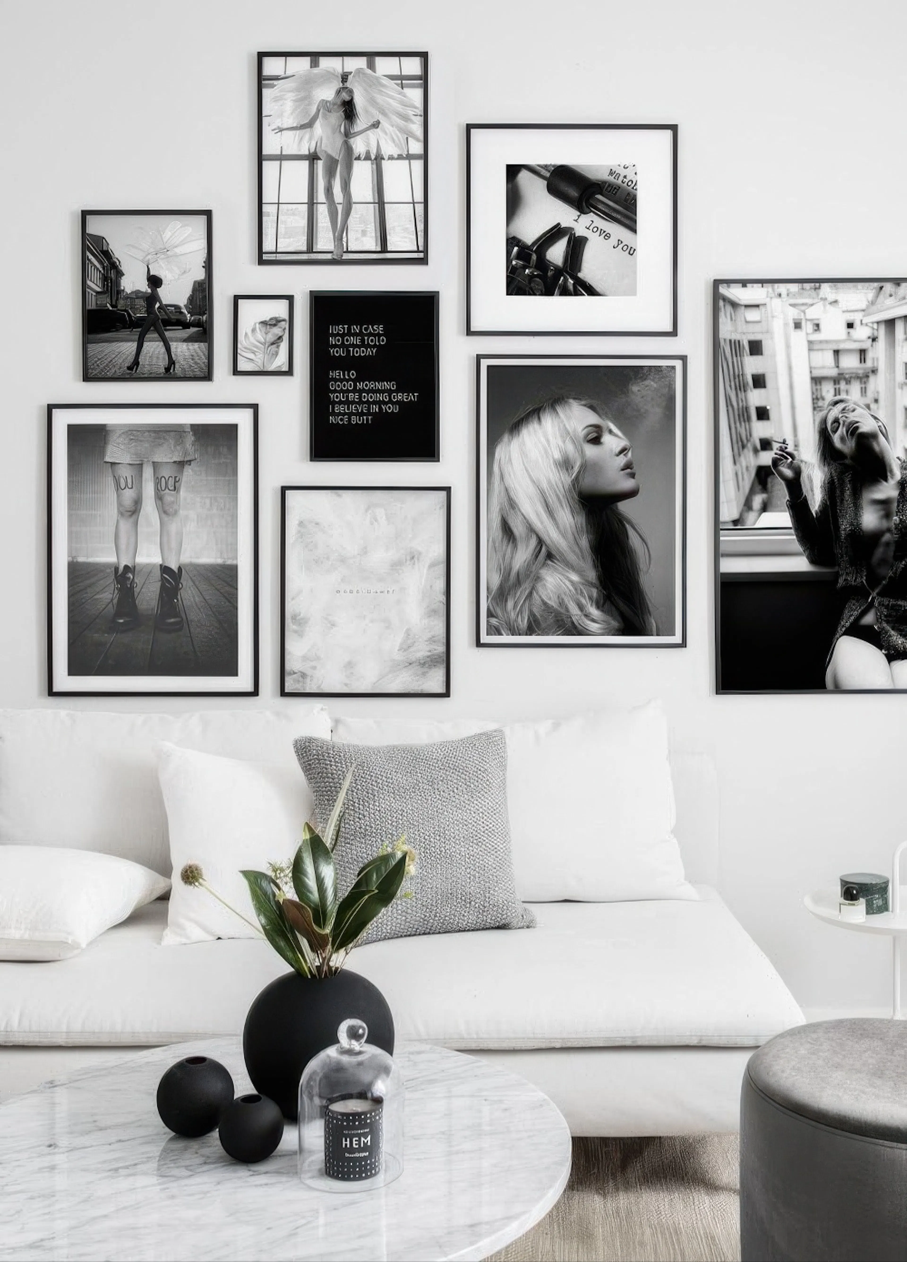 A gallery wall of black and white portrait posters, including an angel, a woman smoking, and typography, displayed above a white