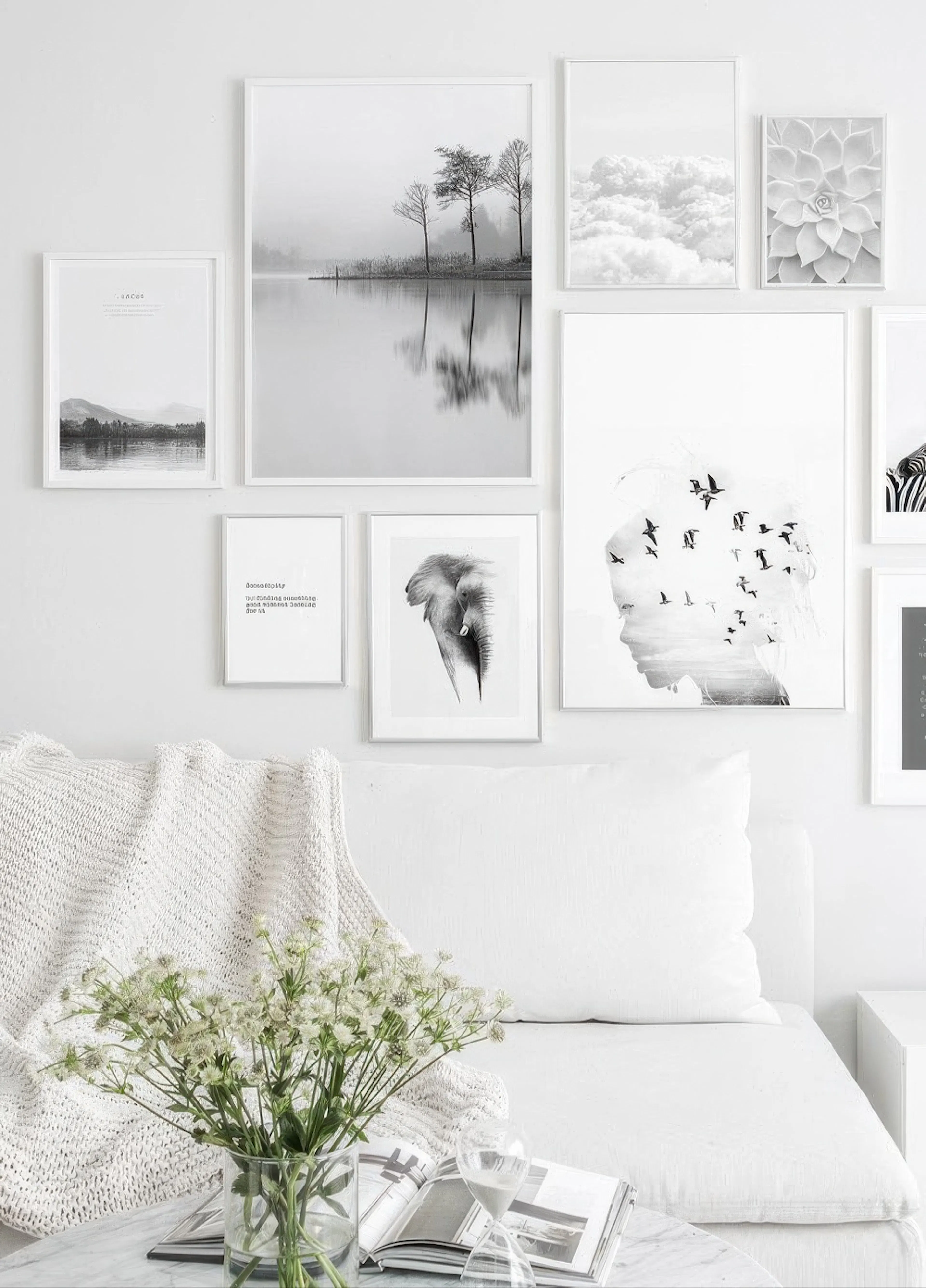 Black and white poster gallery wall with nature, animal, and typography prints, displayed above a white sofa with a knitted thro