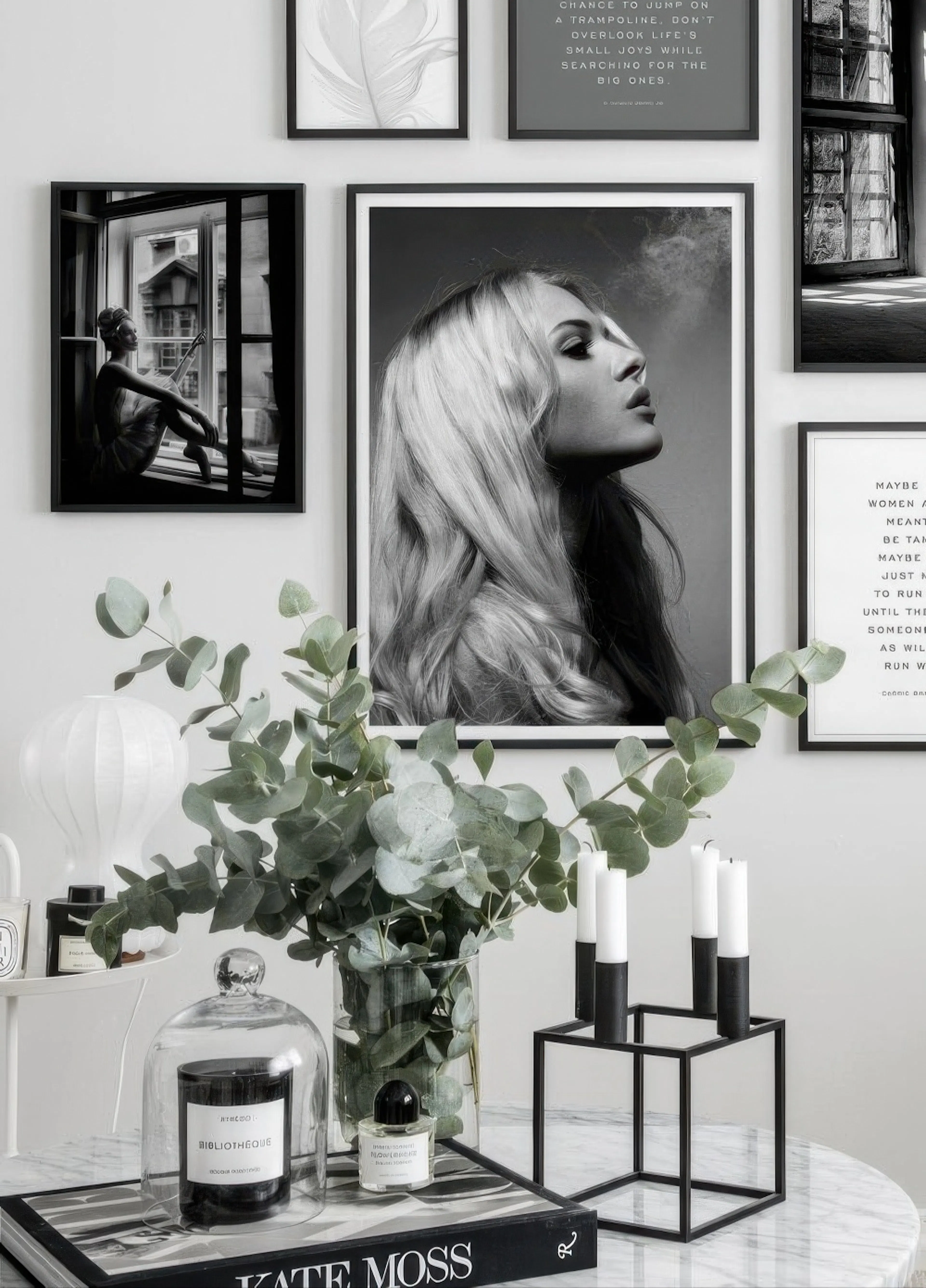 Black and white poster of a woman with long blonde hair, looking up, mounted on a gallery wall with other posters above a marble