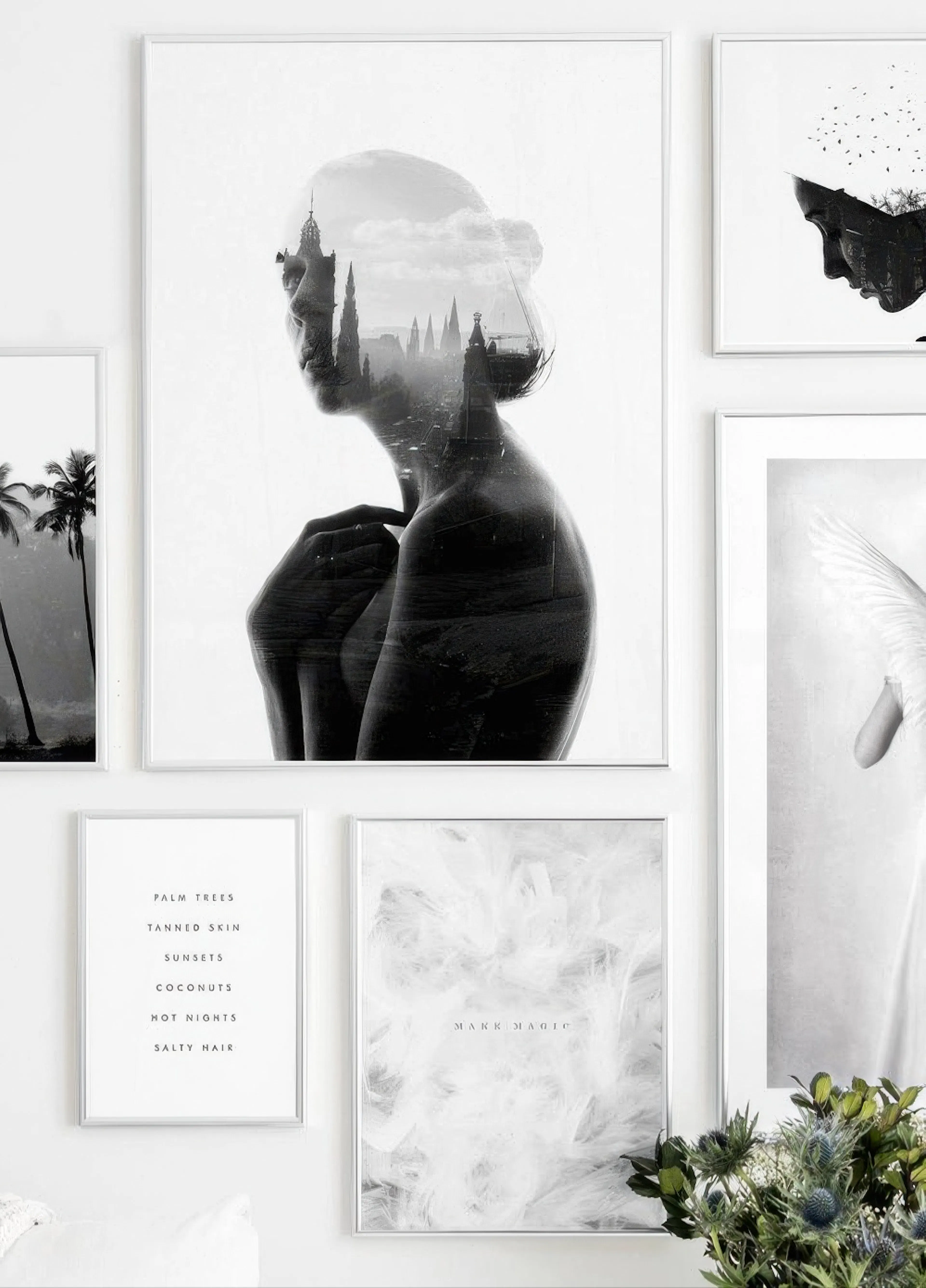 Mustavalkoinen julisteseinä, jossa naisen siluetti ja kaupunkimaisema, kaksi muuta julistetta sekä kasvi.