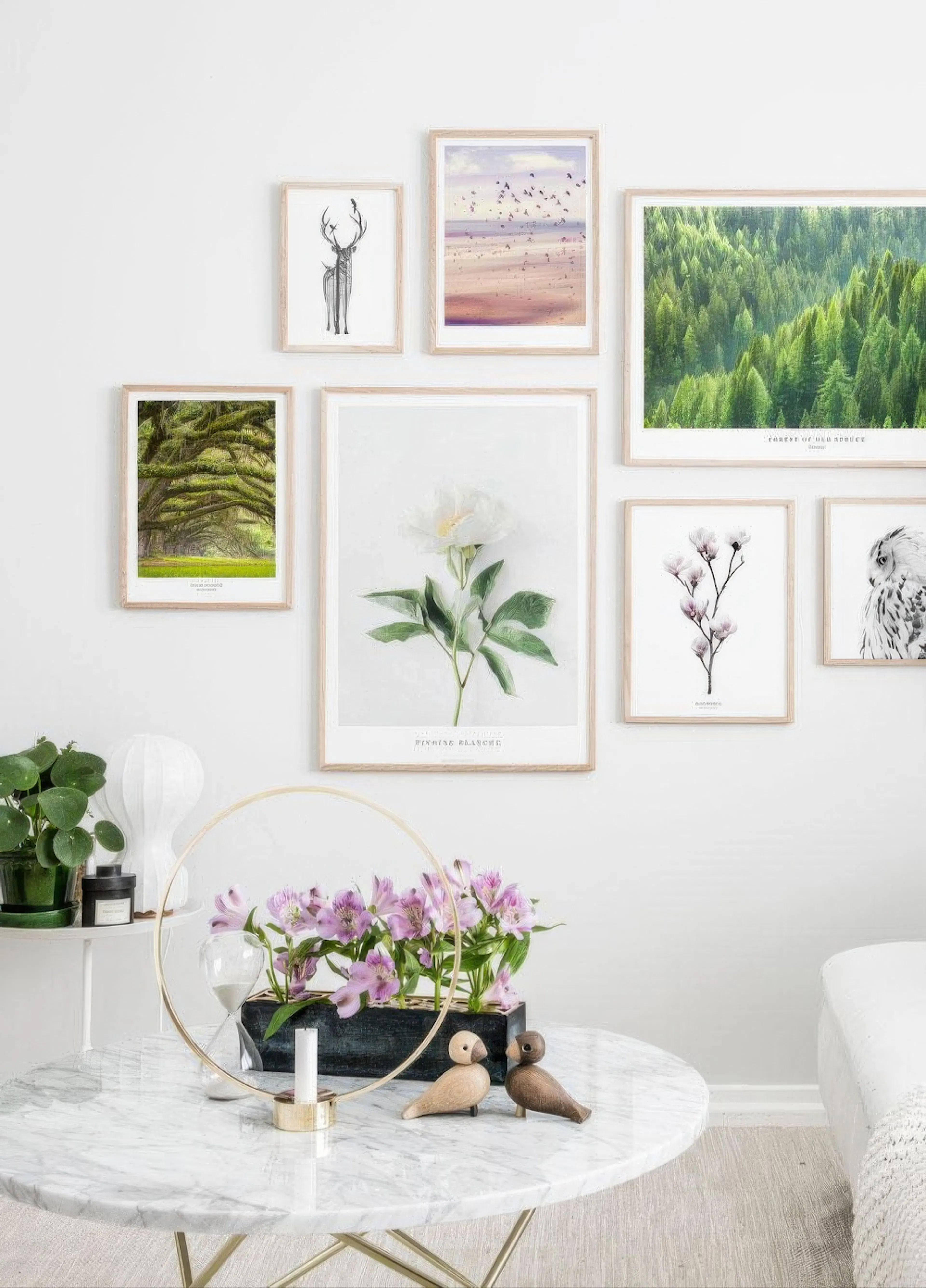 A gallery wall of nature-themed posters, including a forest, beach, and flowers, displayed above a marble coffee table.