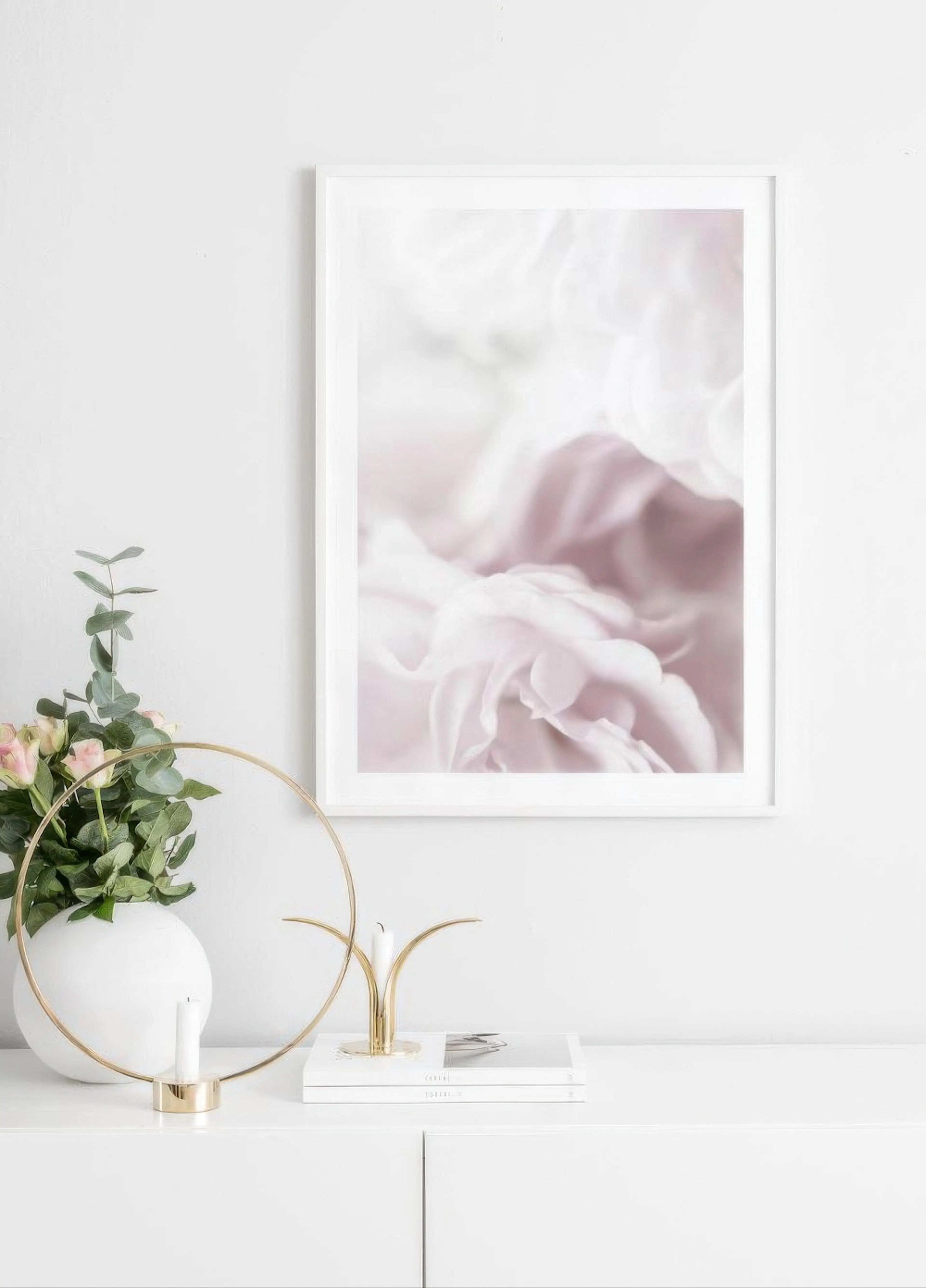 Soft focus floral print with light pink and white petals, displayed above a white cabinet with flowers and candles.