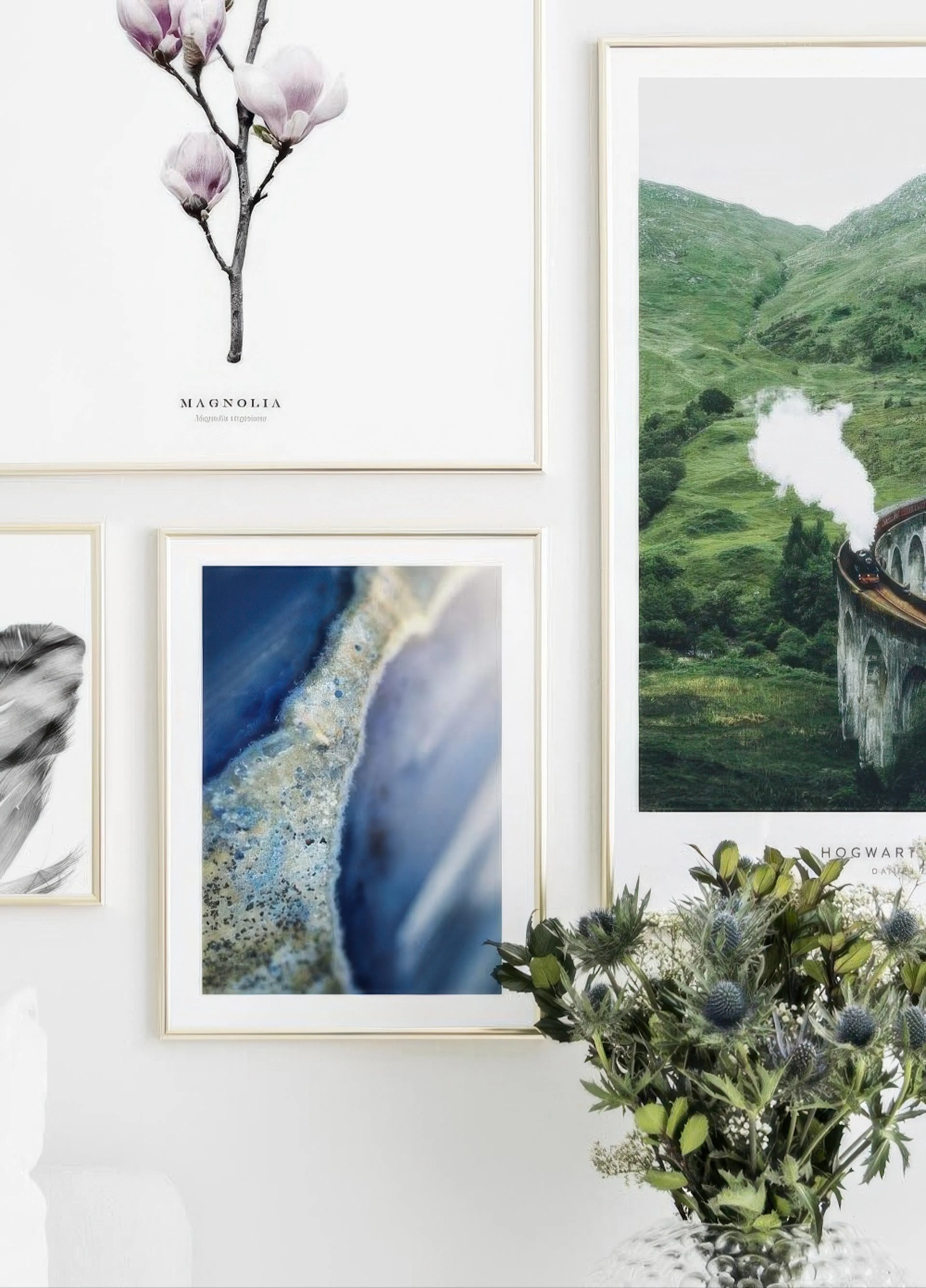 Nástěnná galerie plakátů s magnólií, modrým krystalem a vlakem přes viadukt, v pokoji s vázou květin.