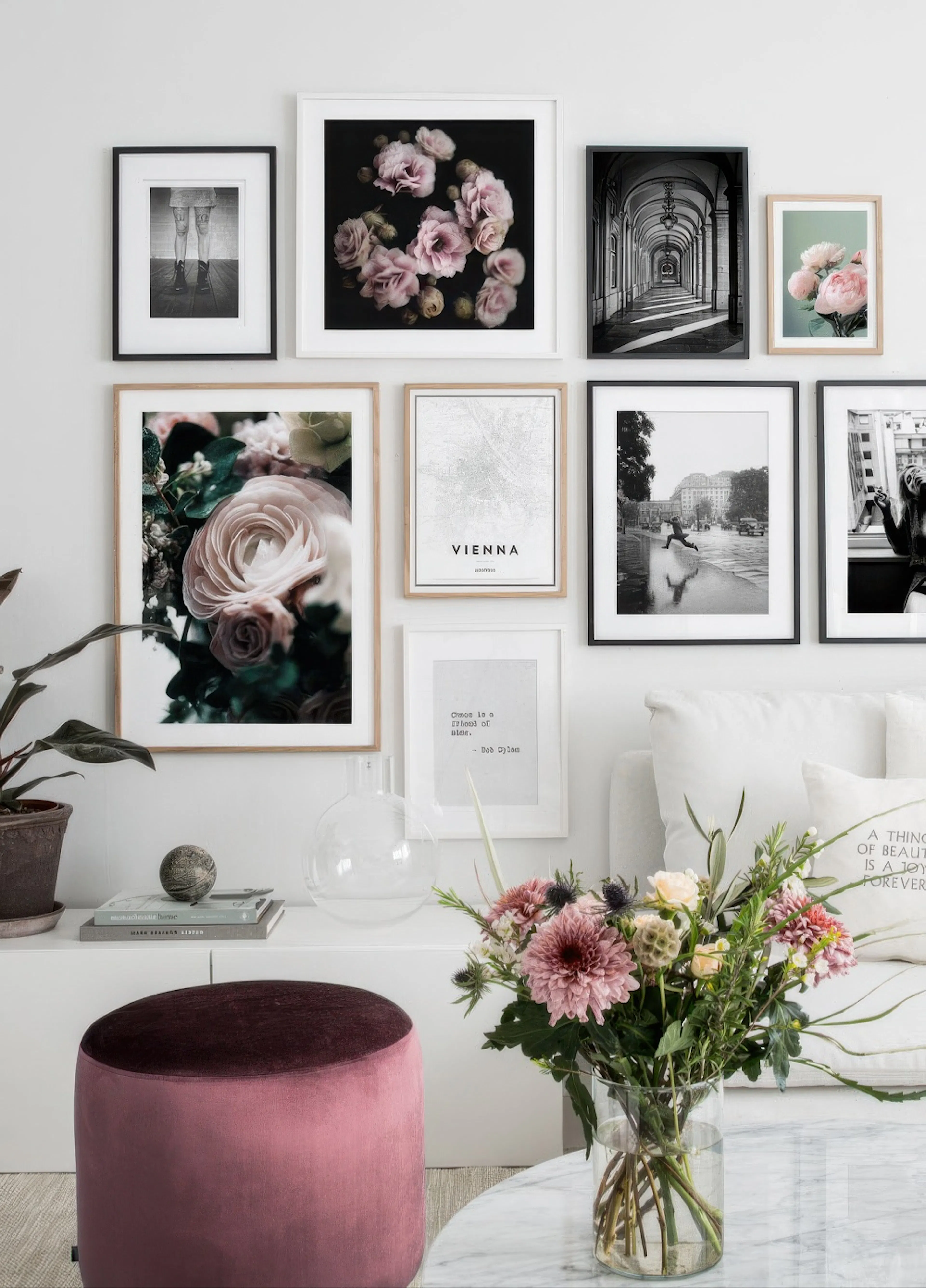 A gallery wall featuring diverse posters including floral, cityscapes, and typography, displayed above a white console table in 