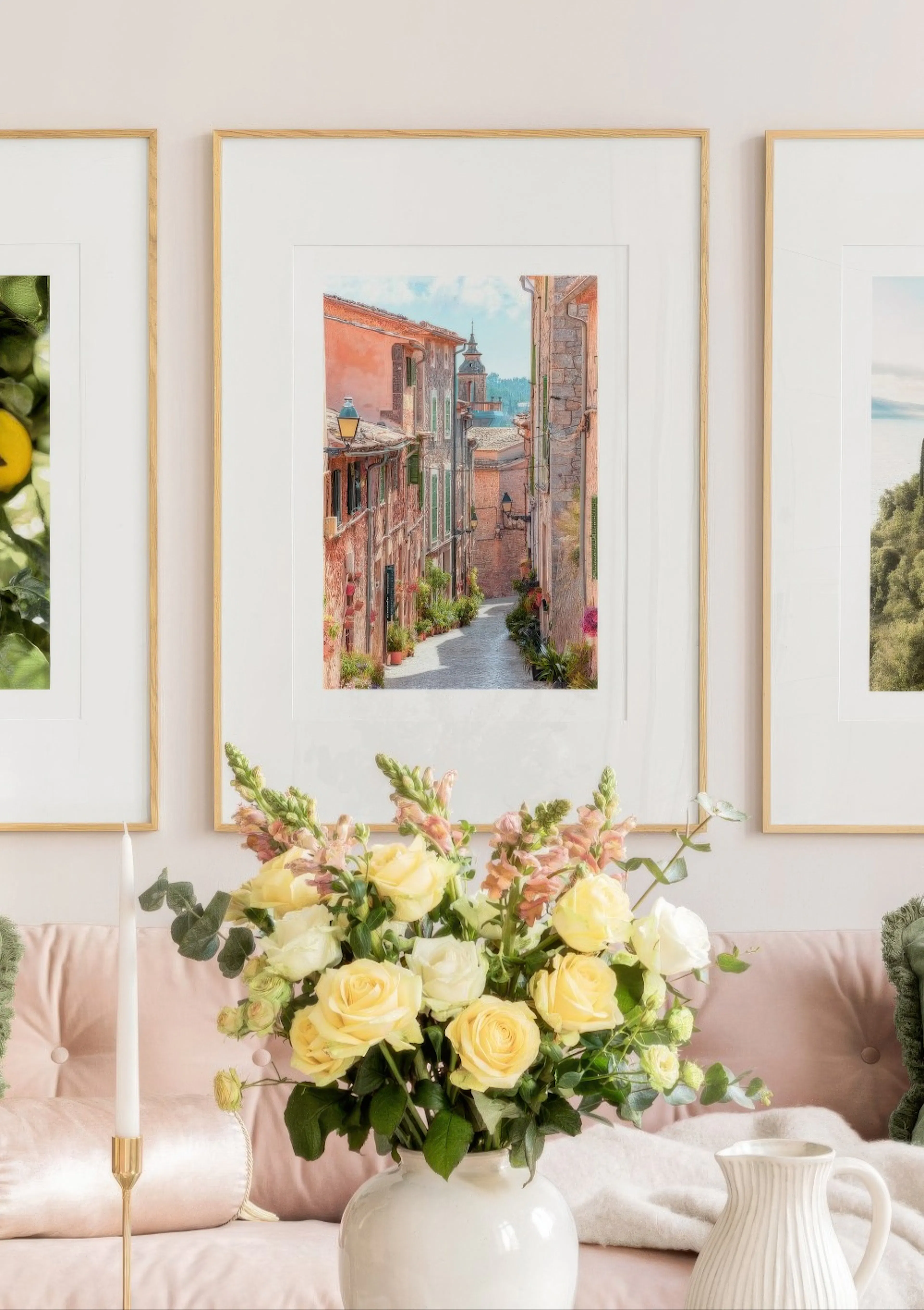 A poster of a charming Italian street scene with terracotta buildings and cobblestones, displayed above a pink sofa with flowers