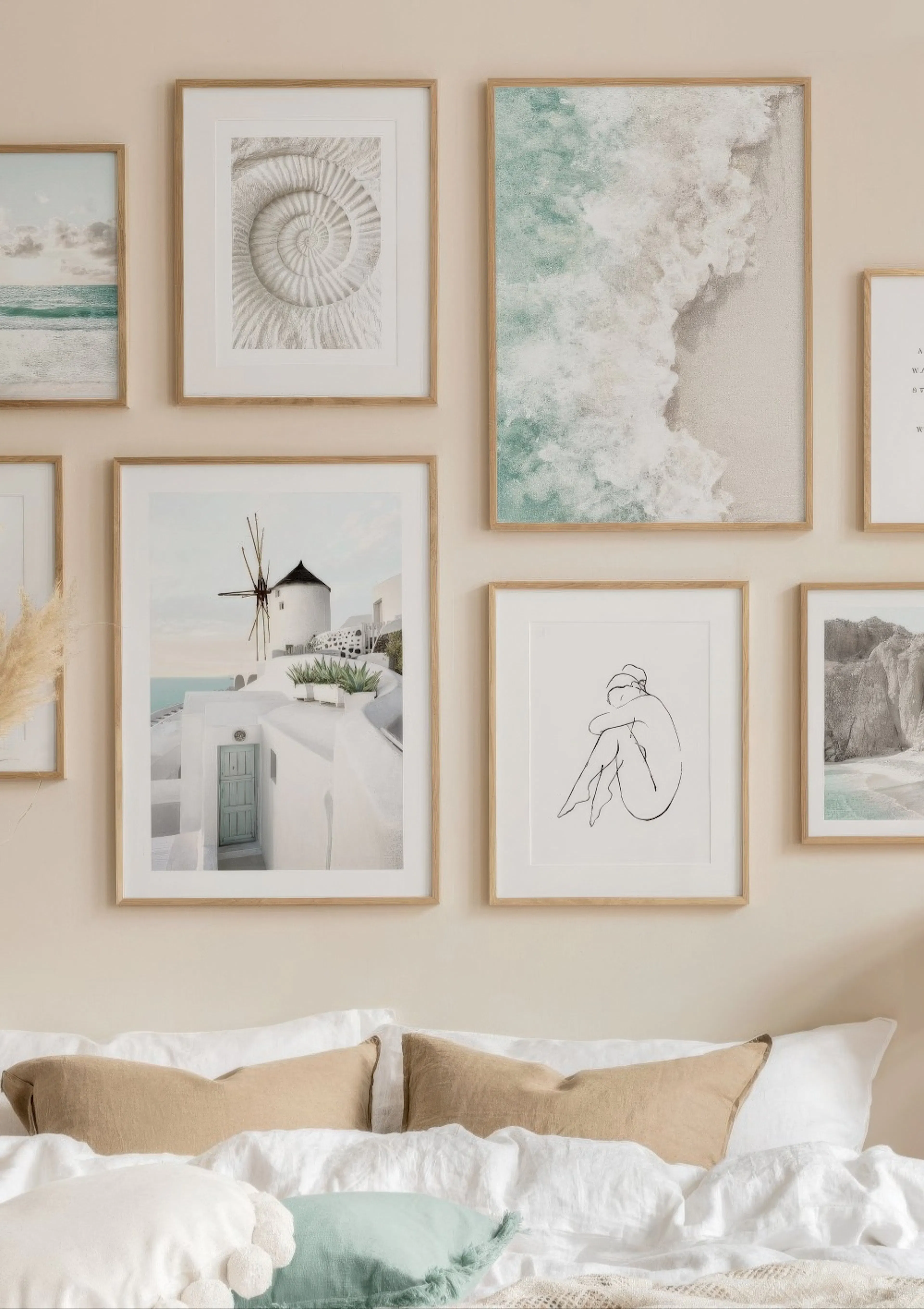 Décoration murale de posters variés, dont une coquille, une mer agitée, un moulin et un dessin de femme, affichée au-dessus dun 