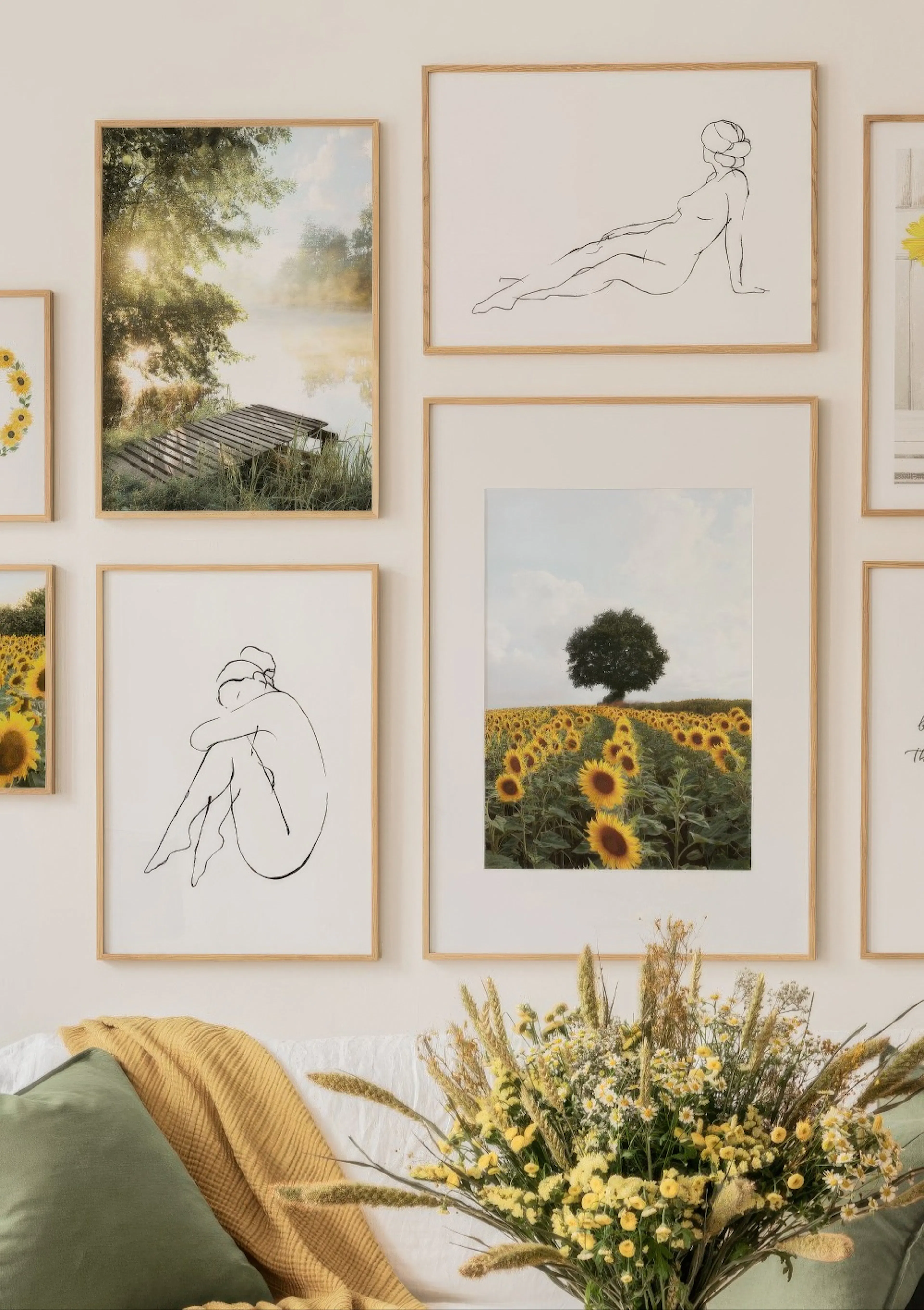 Une décoration murale de six posters, incluant des dessins de nu et des paysages de tournesols, au-dessus dun canapé blanc avec 