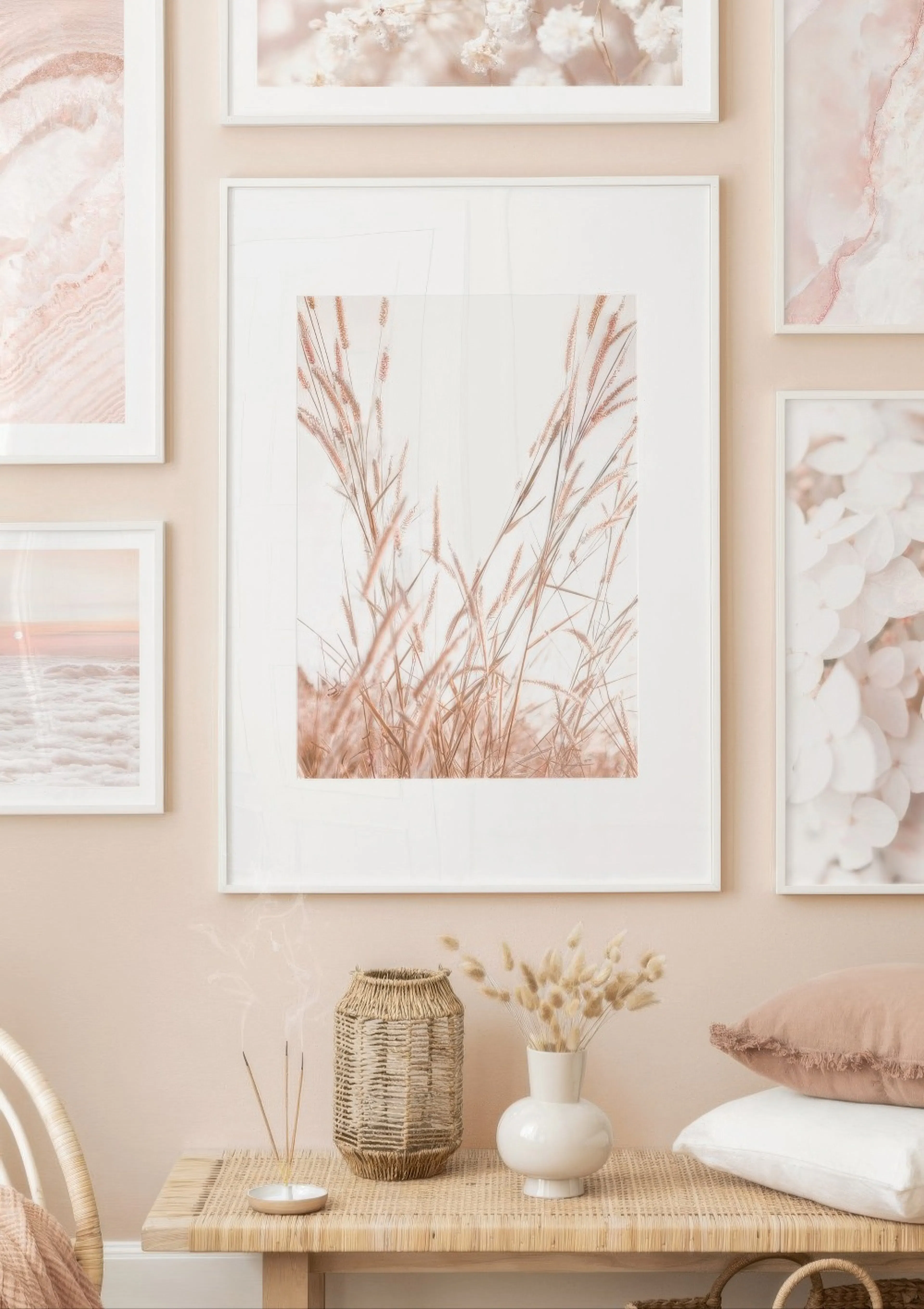 A poster featuring tall, feathery, light brown grass, part of a gallery wall above a woven bench with decor.