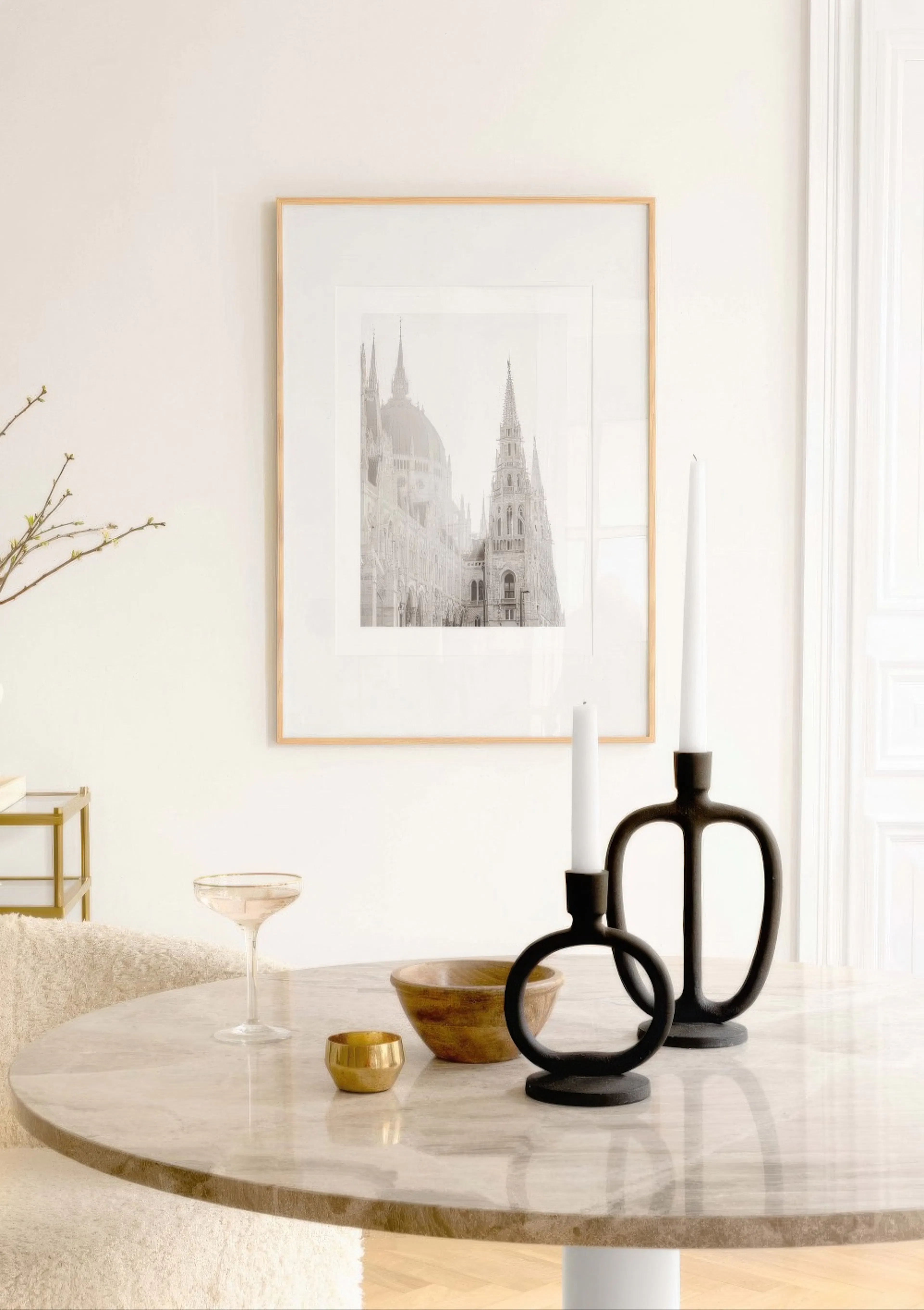 Svartvit poster av ett gotiskt parlament i Budapest, hängande ovanför ett marmorbord med ljusstakar.