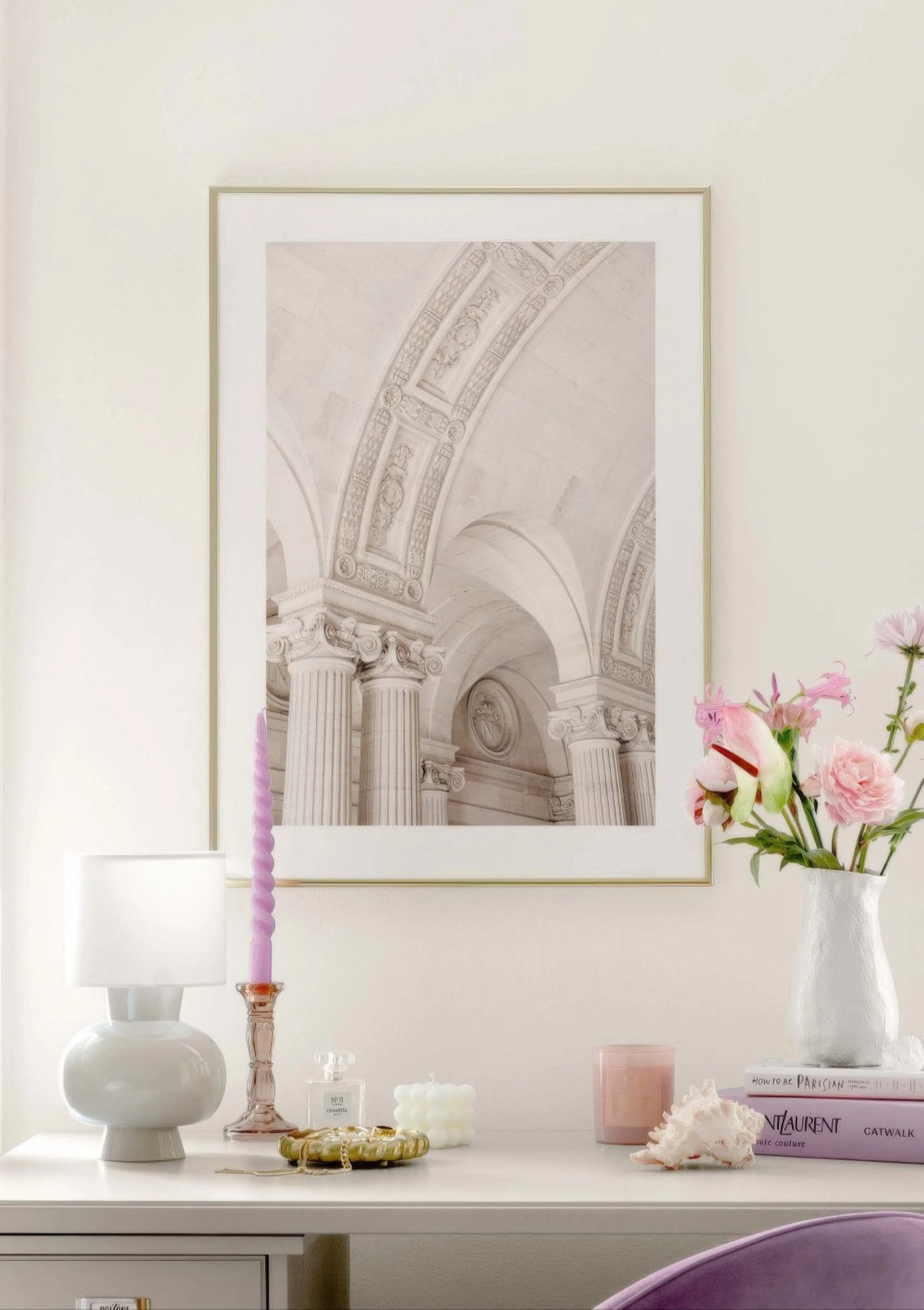 A poster featuring a close-up of classical architectural arches and ornate pillars in light tones, displayed above a white desk 