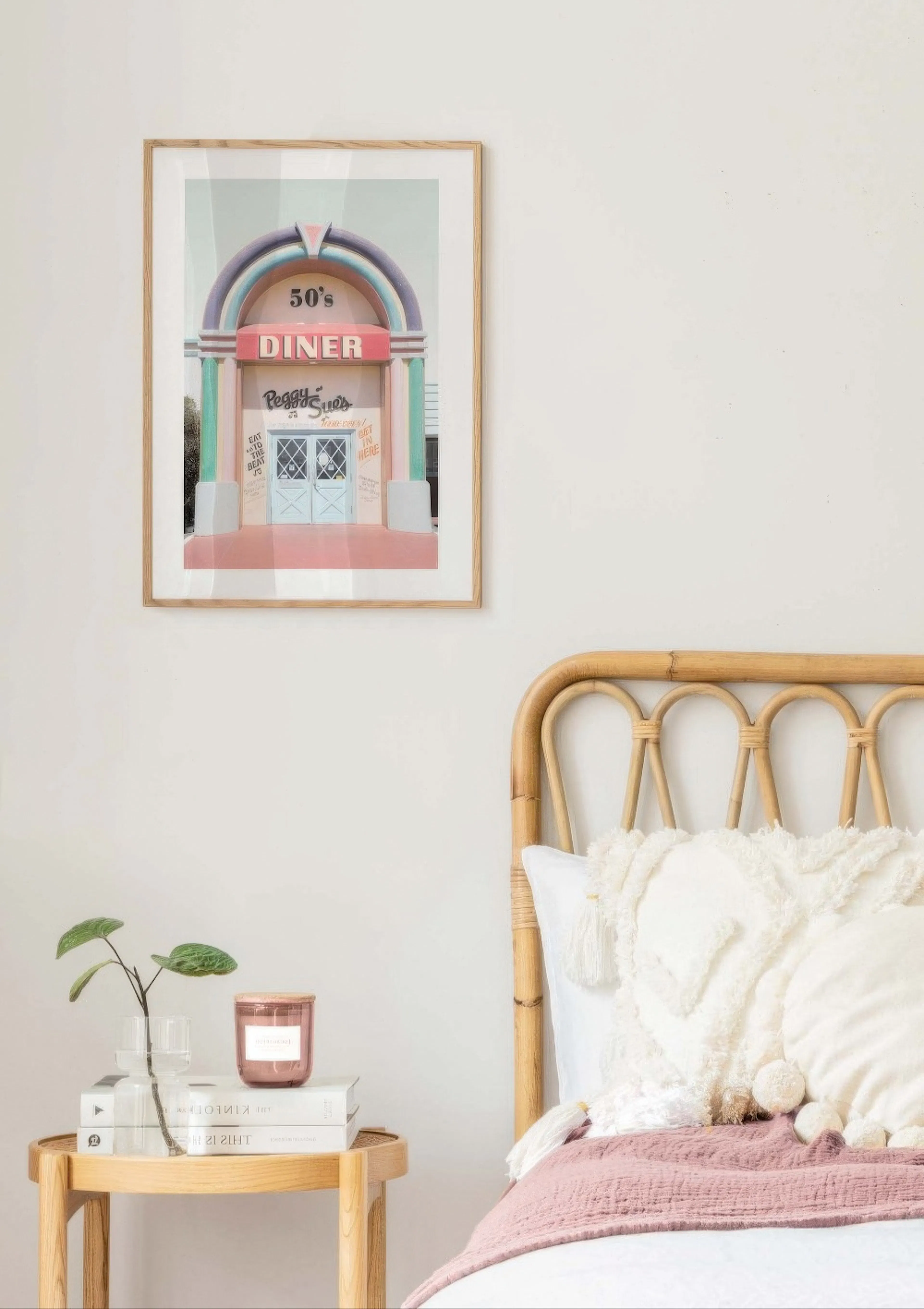 ピンクとミントグリーンのレトロなダイナーのポスターが、寝室のベッドサイドに飾られている。