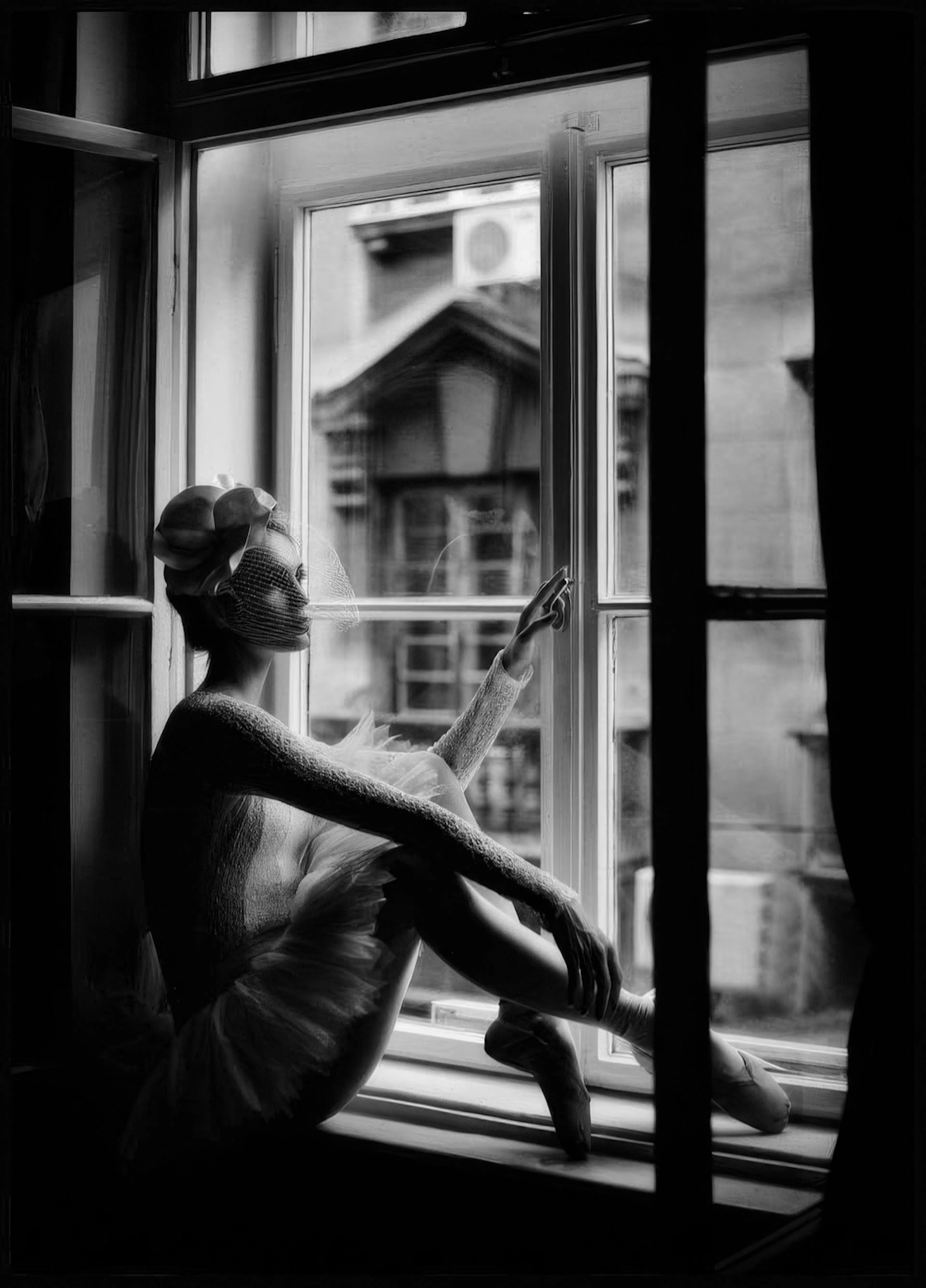 Schwarz-Weiß-Poster einer Ballerina mit Schleier und Federkleid, die im Fenster sitzt und nachdenklich hinausschaut.