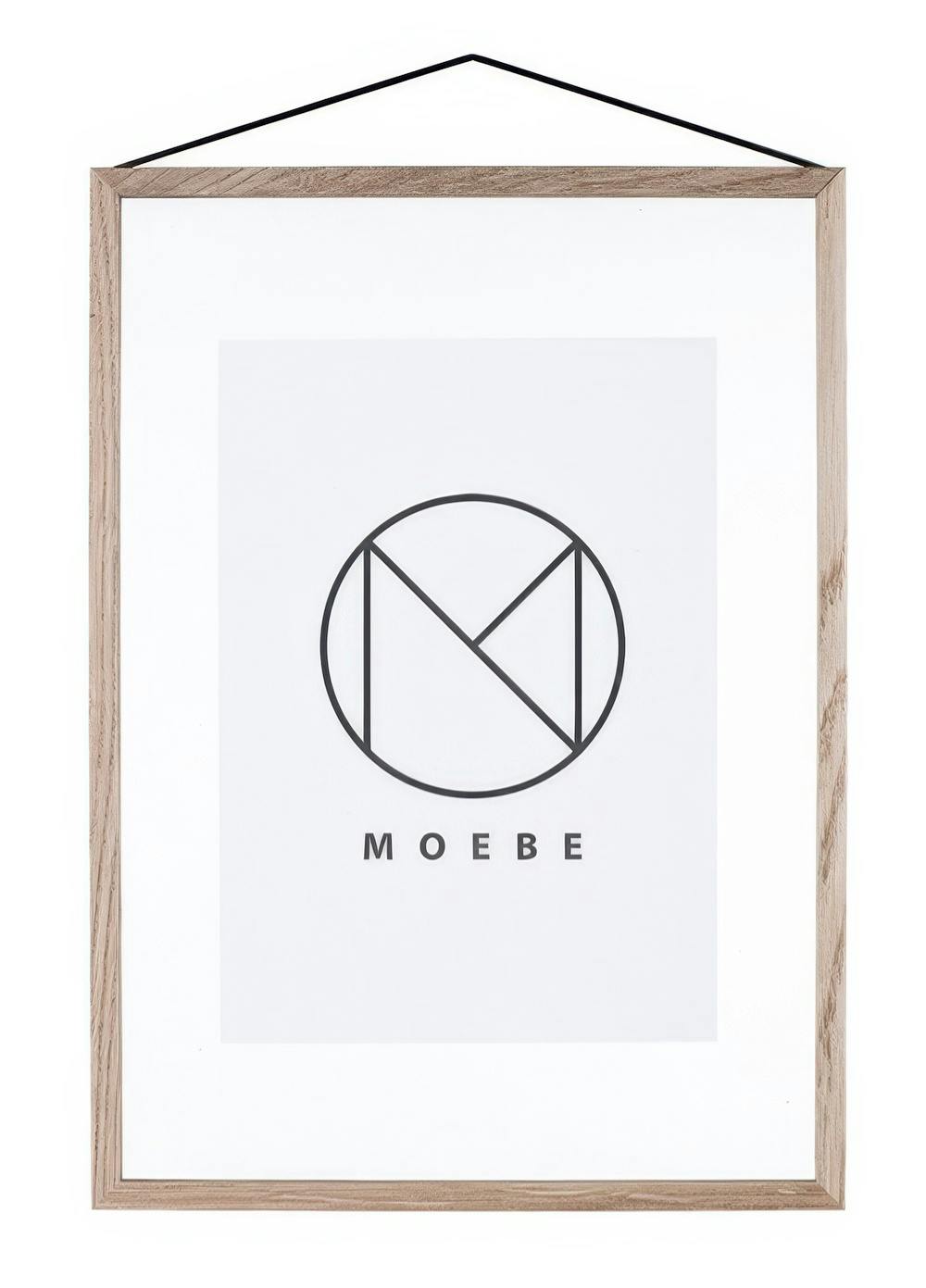 A poster featuring a black geometric logo with a circle and intersecting lines, with MOEBE text below, in a light wooden frame.