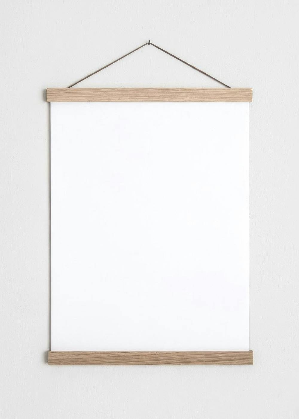 A blank white poster, held by light wood magnetic poster hangers and a string, against a textured white wall.