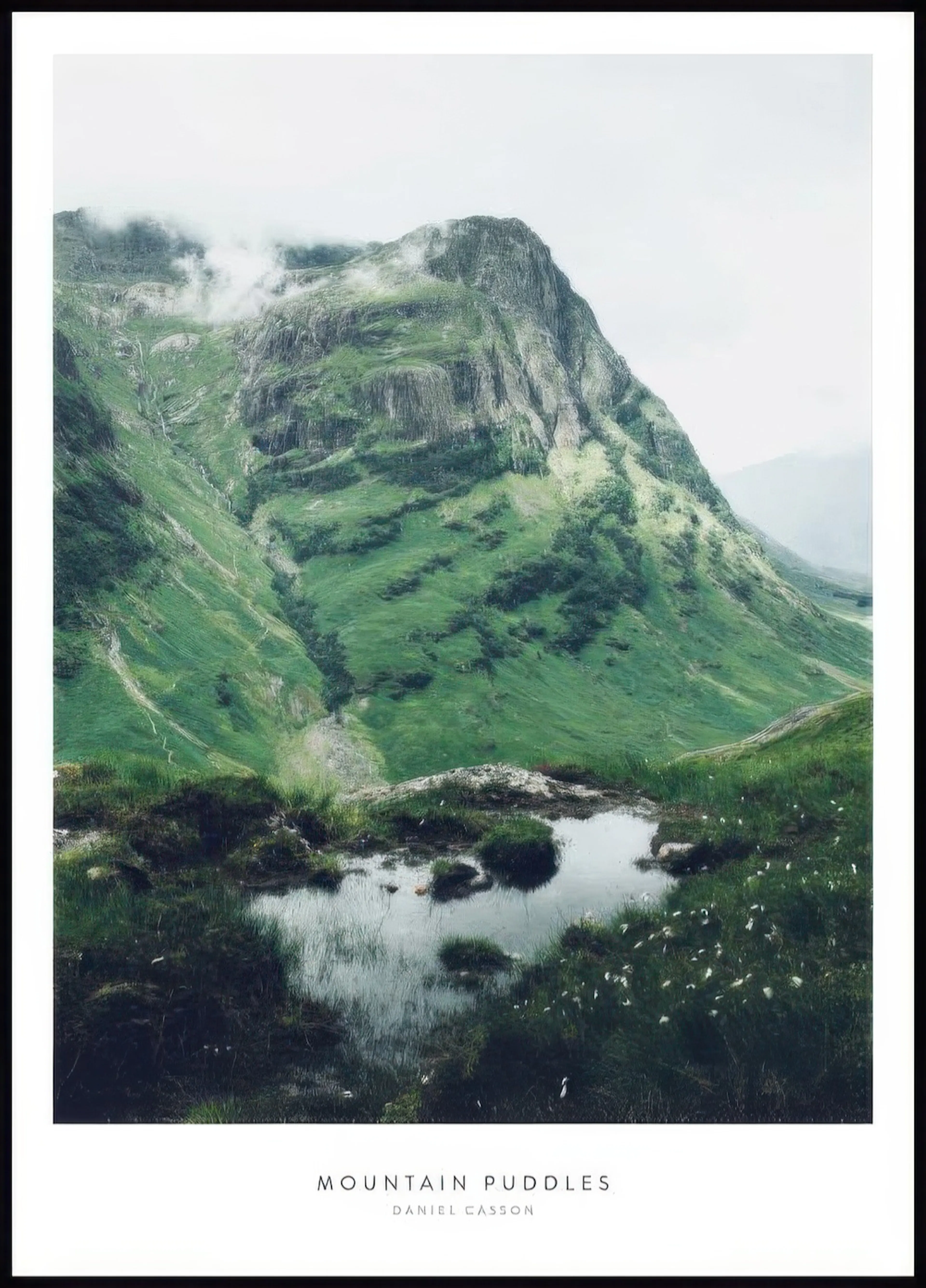 A poster featuring a green mountain landscape with a small reflective puddle and grass in the foreground.