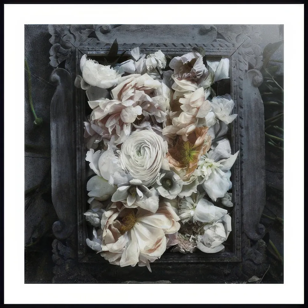 A poster featuring a dark, distressed frame filled with an arrangement of light-colored, muted flowers.