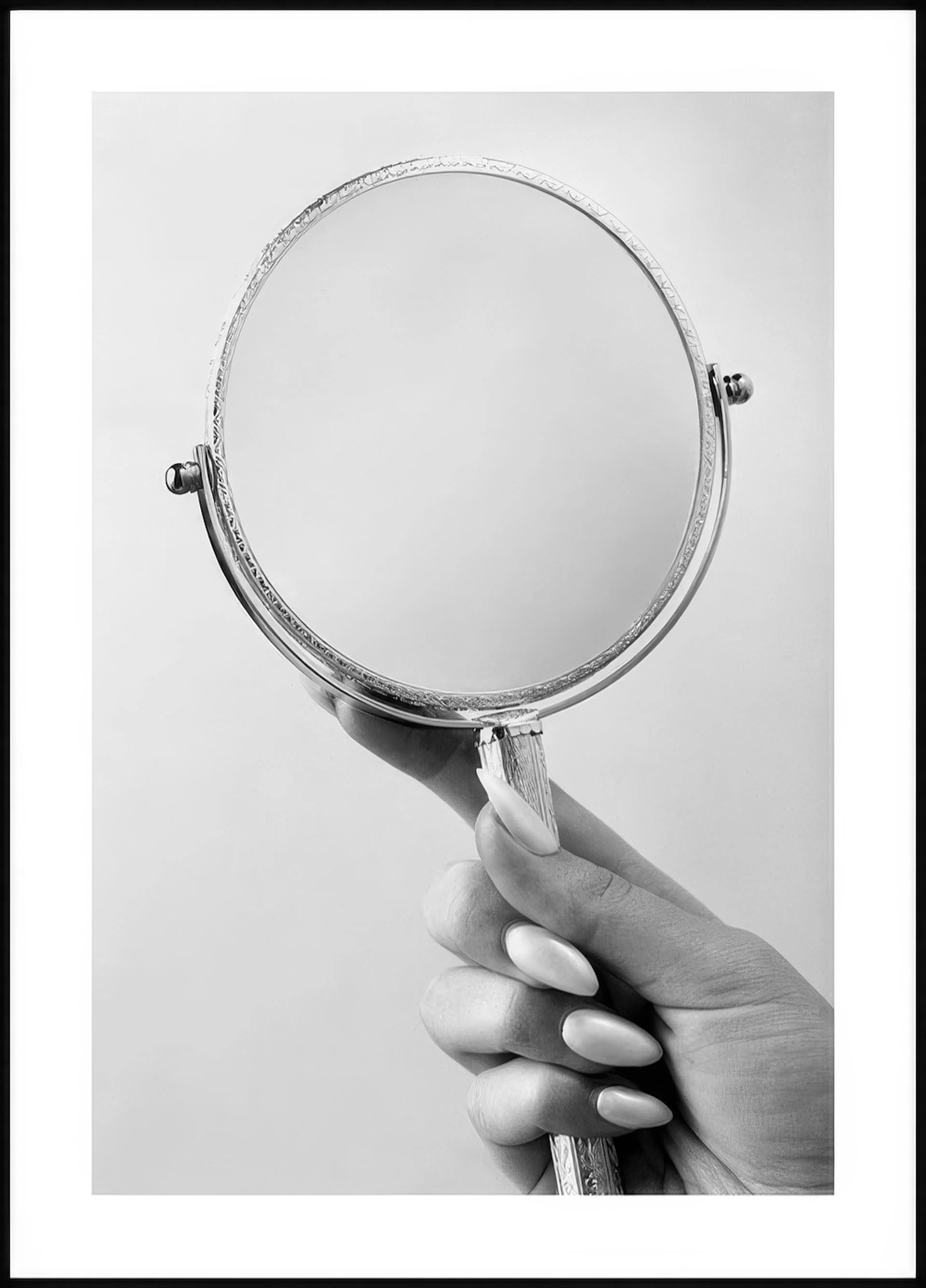 Mustavalkoinen juliste, jossa käsi pitelee pyöreää, koristeellista peiliä. Käden kynnet ovat pitkät ja terävät.