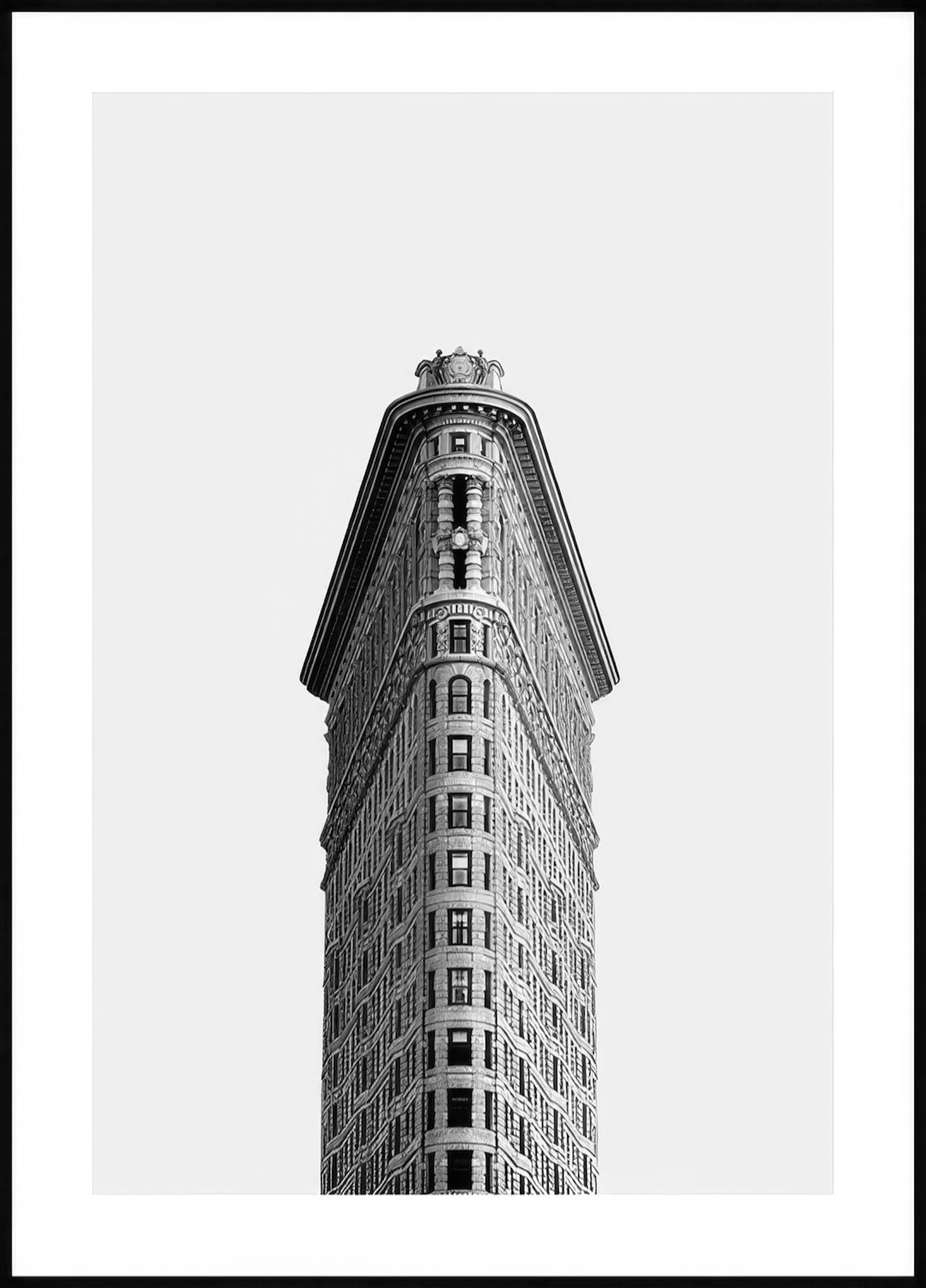 A poster of the iconic Flatiron Building in New York City, featuring its distinctive triangular shape in striking black and whit