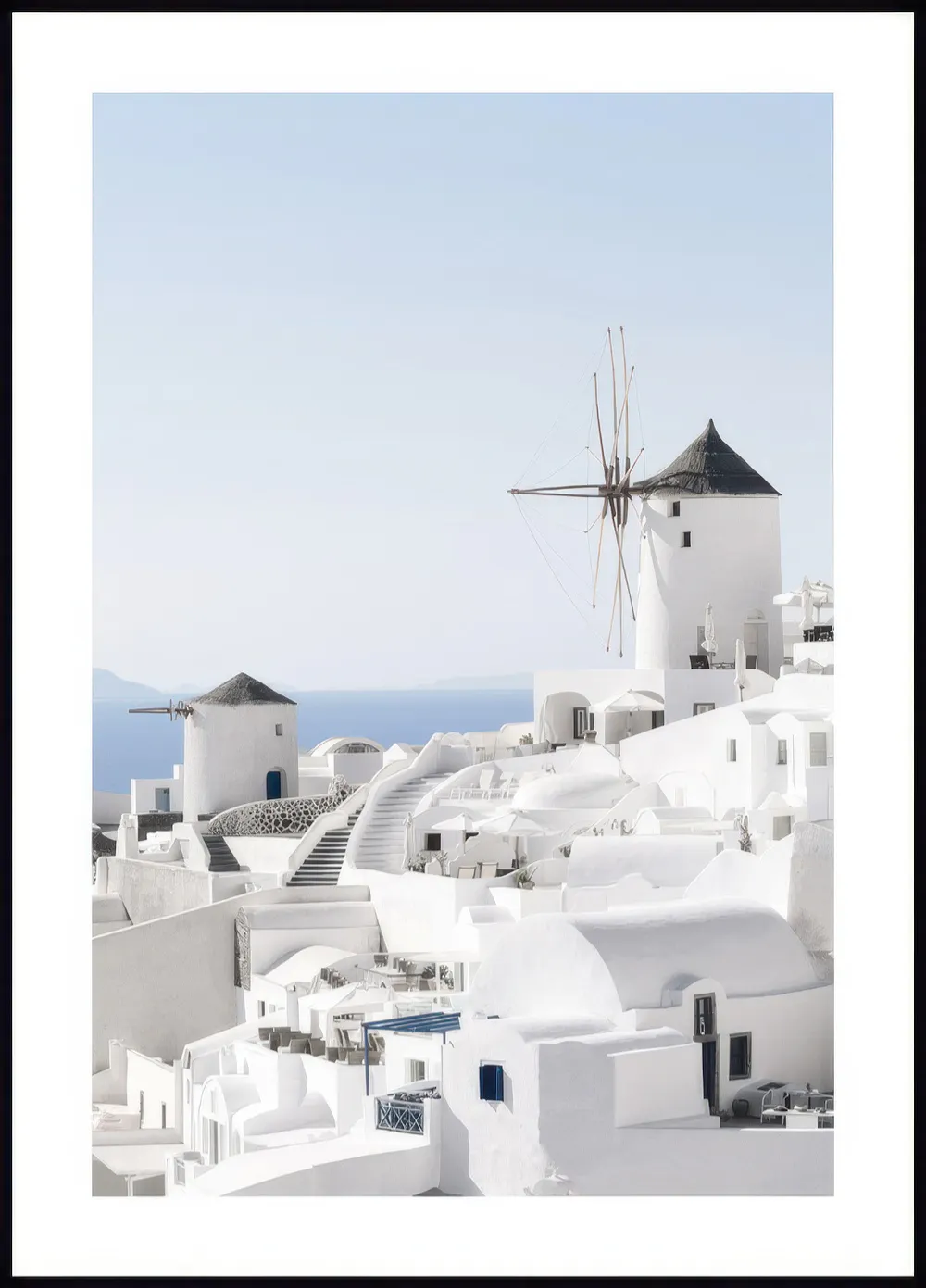 A poster featuring iconic white buildings and windmills overlooking the blue sea in Santorini, Greece.