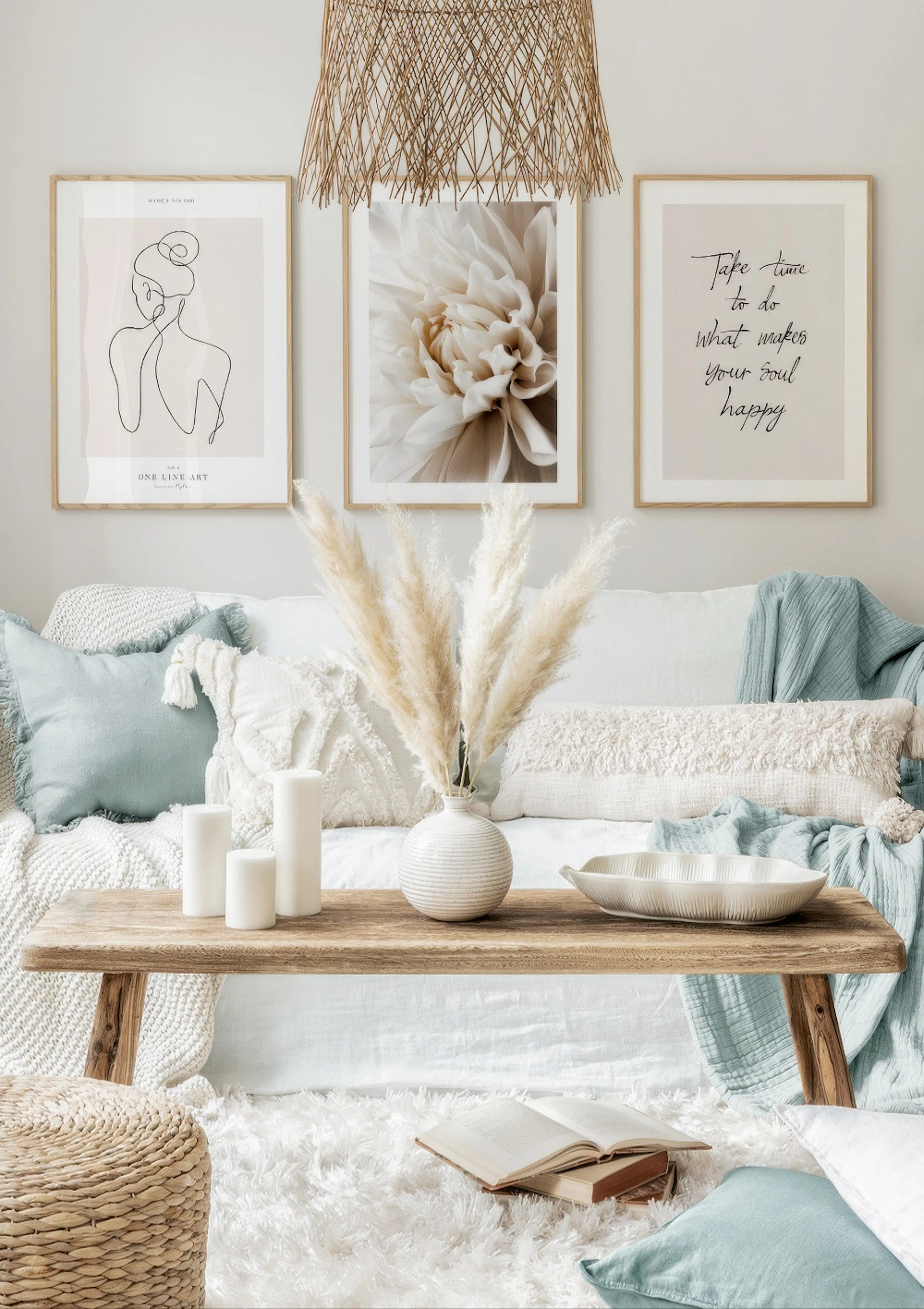 En plakatpakke med en abstrakt kvindefigur, en dahlia i beige nuancer og et citat på lyse baggrunde, hængende over en sofa.