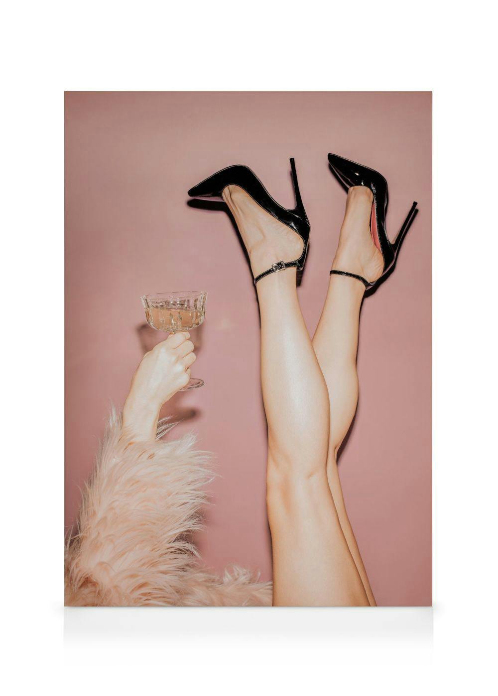 Canvas met een close-up van benen met zwarte hoge hakken tegen een roze achtergrond, en een hand met een glas champagne.