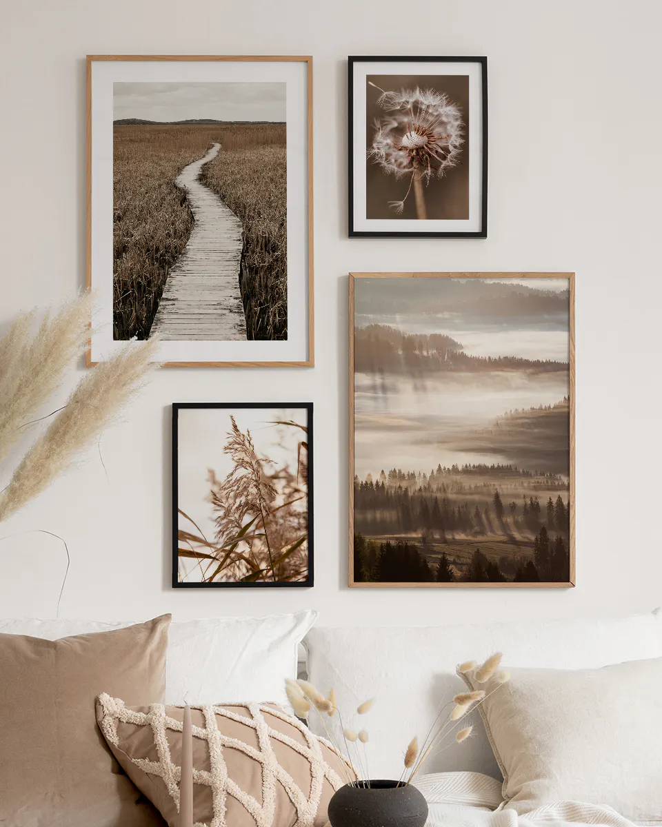A gallery wall with four nature-themed prints, including a wooden boardwalk, a dandelion, tall reeds, and a misty forest, displa