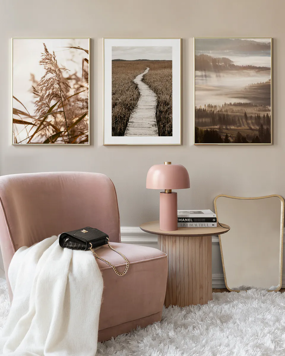 A gallery wall with three nature prints: tall reeds, a boardwalk through tall grass, and a foggy forest.