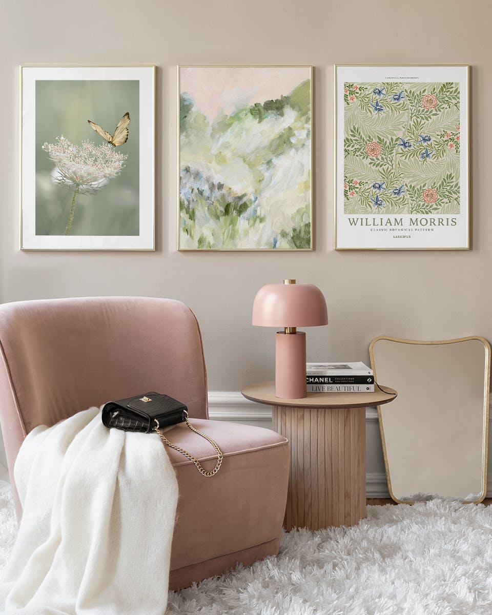 Drei verschiedene Poster in einem Wohnzimmer: ein Schmetterling auf einer Blume, ein abstraktes Bild in Grün- und Rosatönen und
