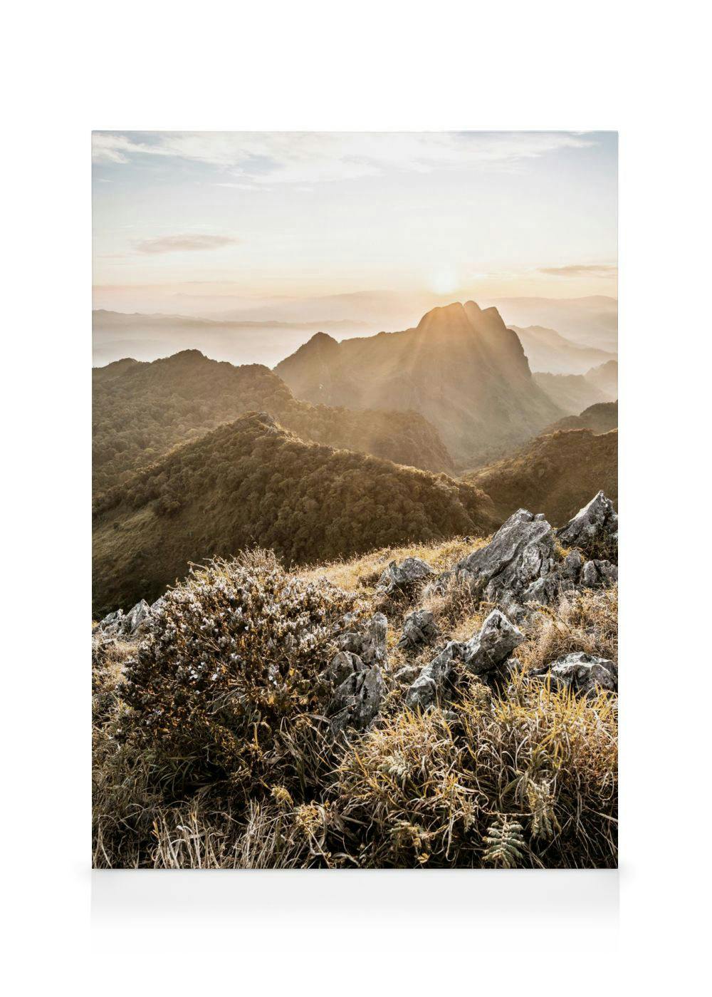 Leinwandbild mit einer Berglandschaft bei Sonnenaufgang, goldene Gräser und Felsen im Vordergrund.