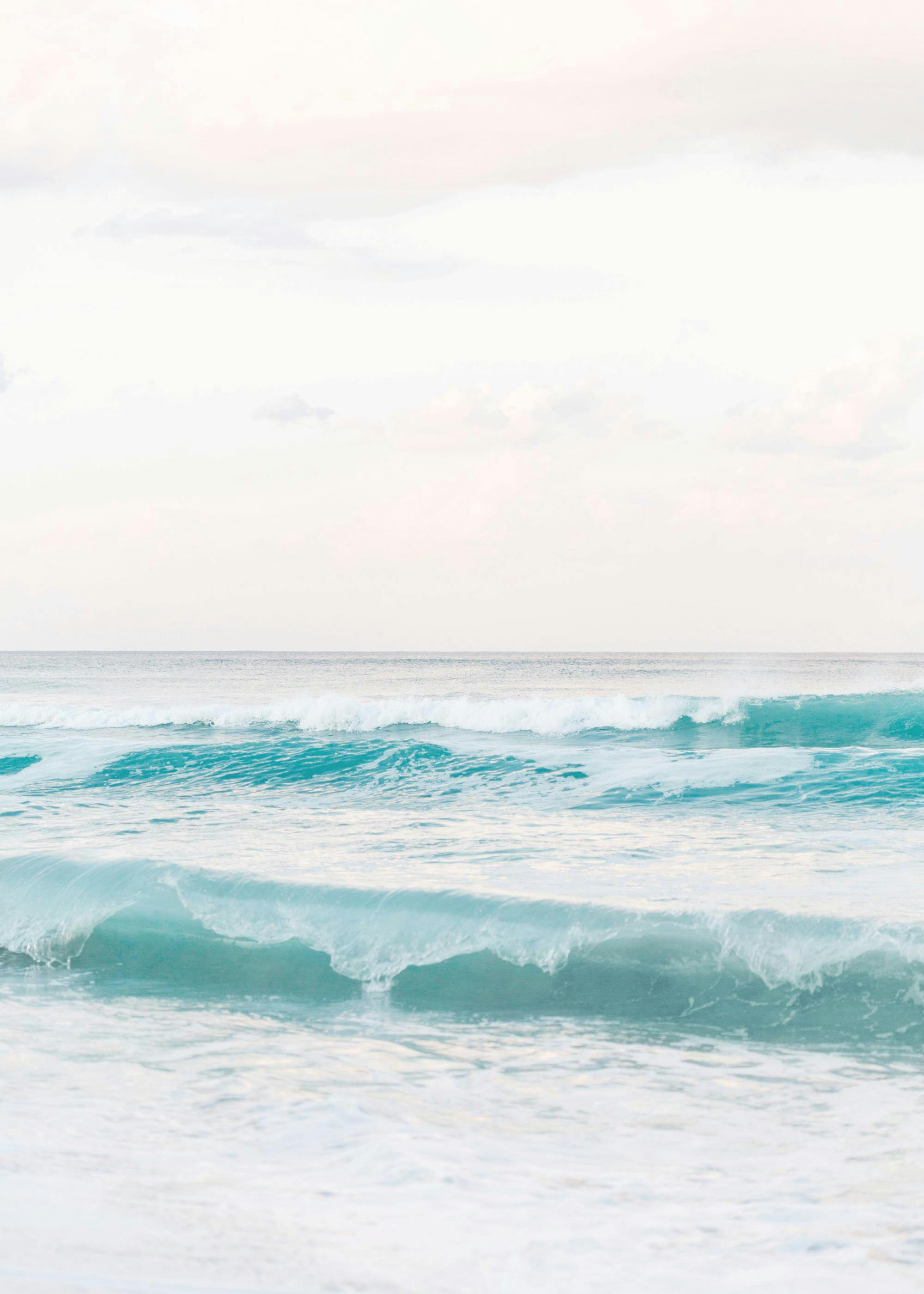 A poster depicting a serene ocean scene with light turquoise and blue waves under a pale sky.