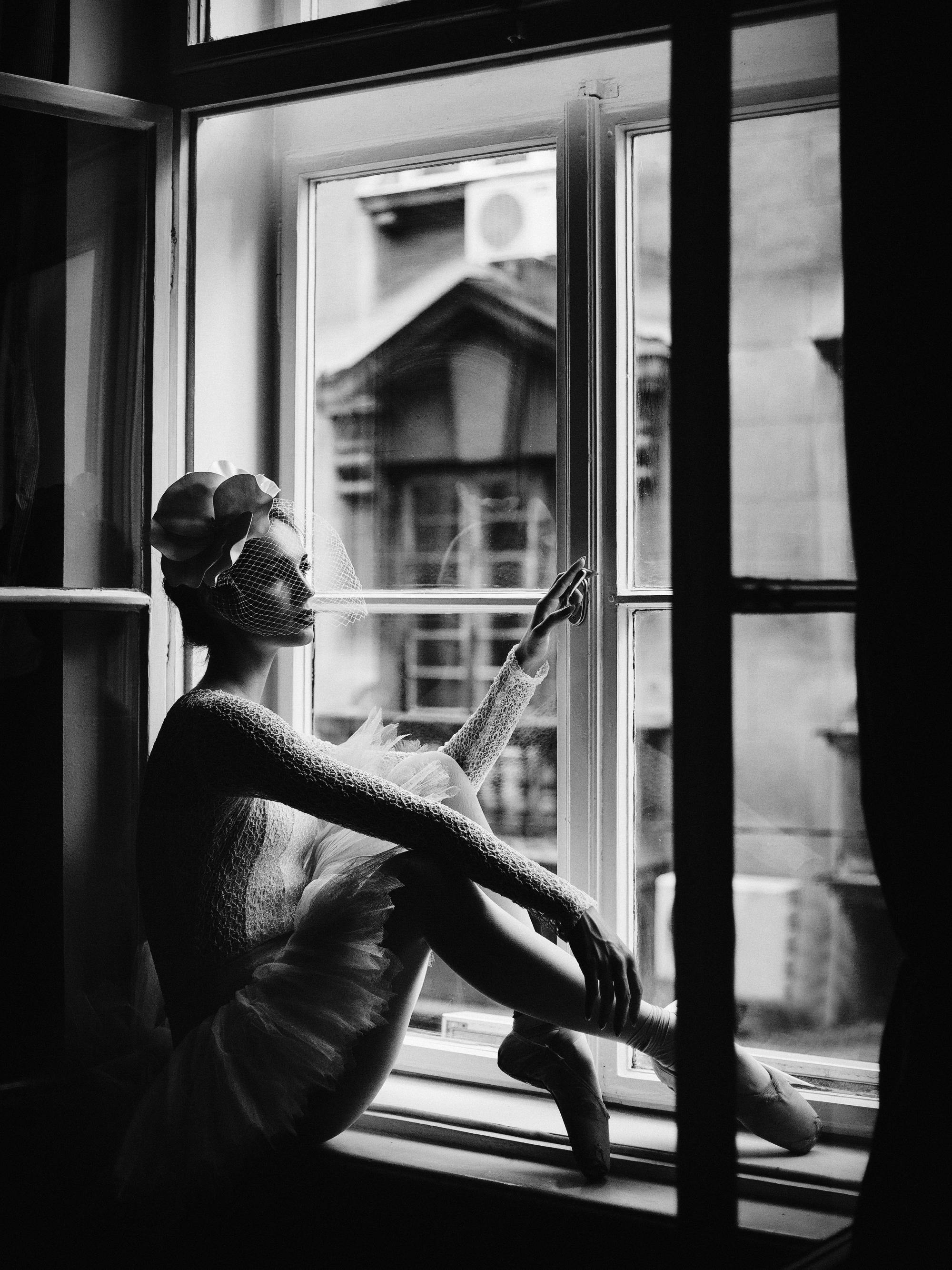 窓辺に座り外を見つめるバレリーナを描いたポスター。モノクロームでクラシックな雰囲気。