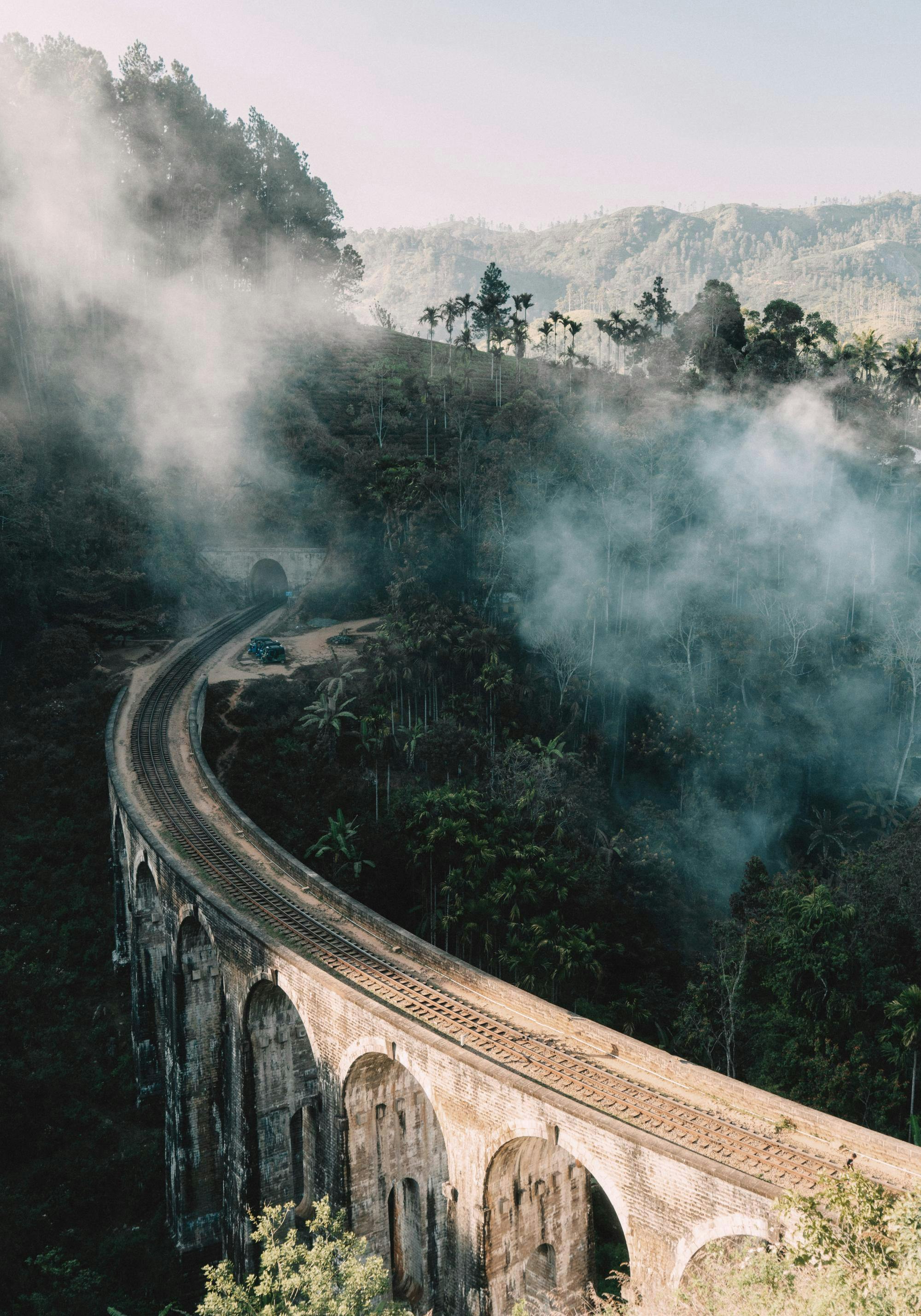 Upea juliste Sri Lankan Nine Arch -sillasta, jota ympäröivät sumuiset kukkulat ja tiheä kasvillisuus.