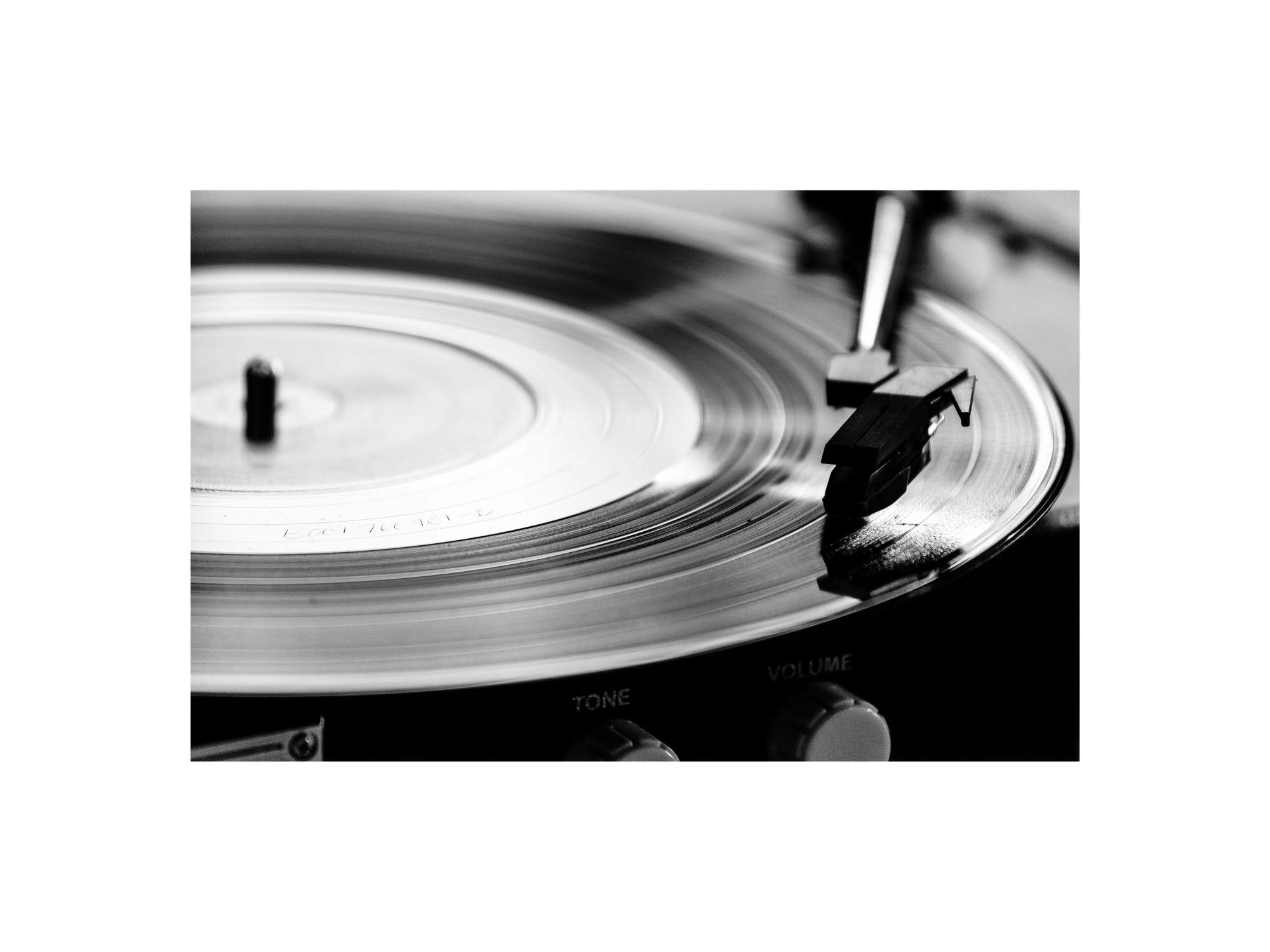 Mustavalkoinen juliste, jossa lähikuva pyörivästä vinyylilevystä levysoittimessa.