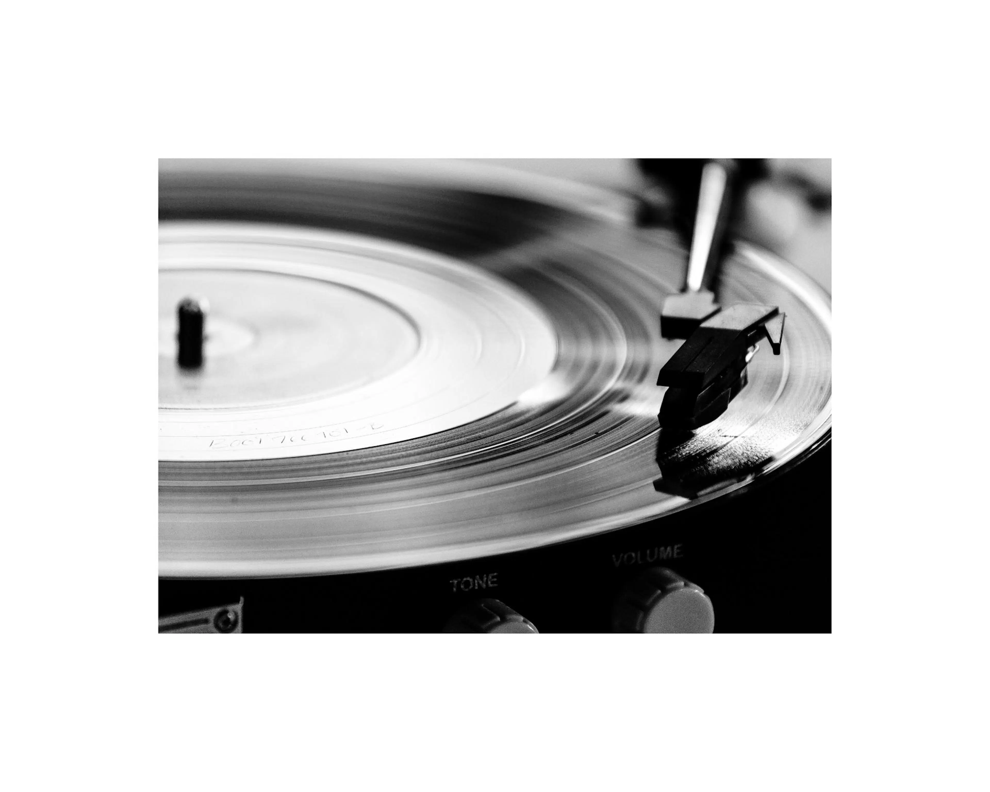 Póster de un tocadiscos vintage en blanco y negro, con un disco de vinilo girando y la aguja sobre él.