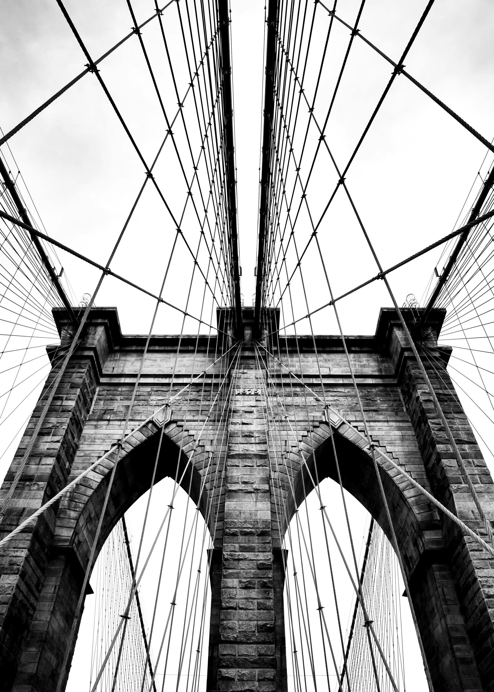 A poster of the Brooklyn Bridge in black and white, showing its iconic stone arches and intricate suspension cables.
