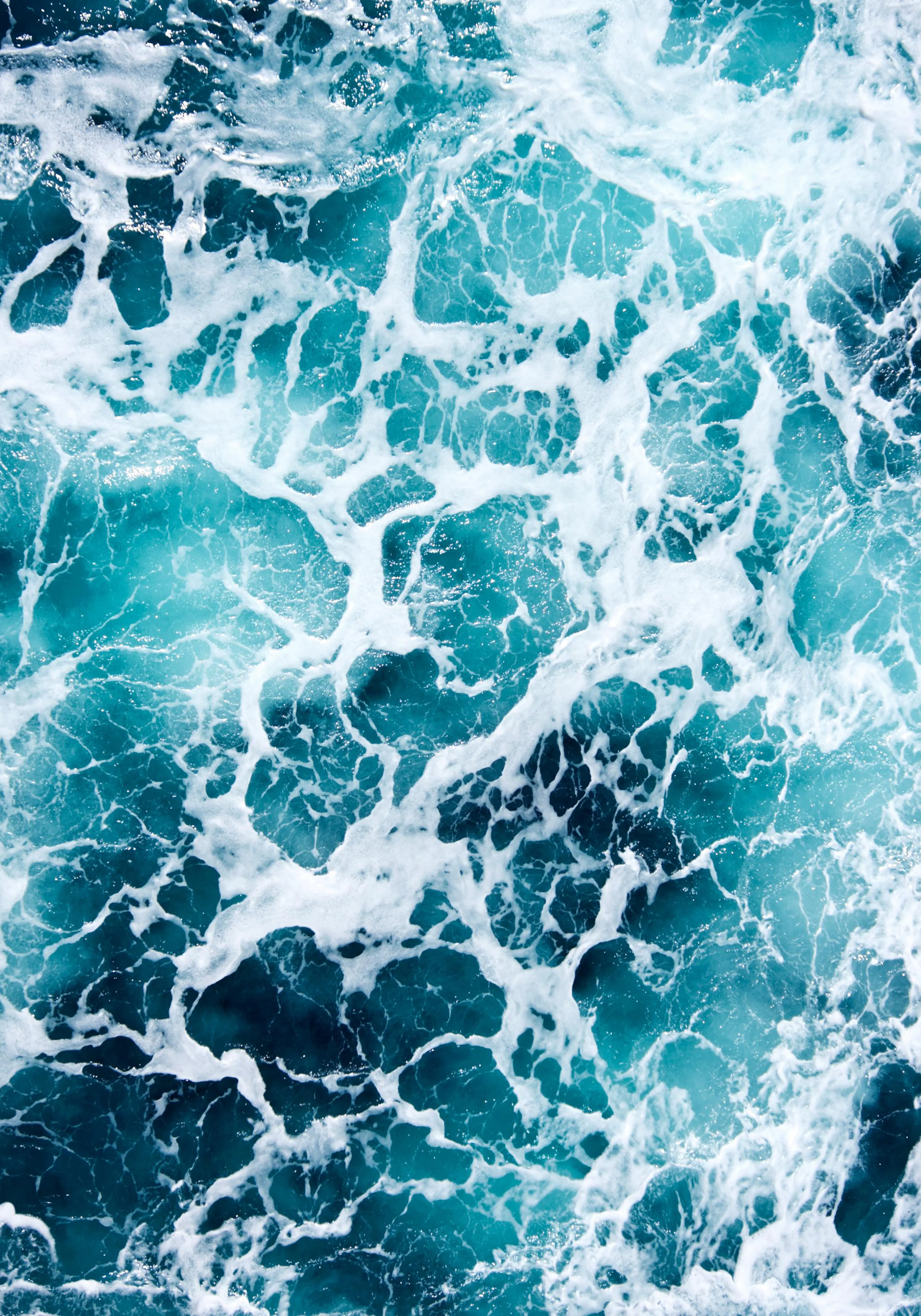 Un poster des vagues deau turquoise et bleu foncé avec de lécume blanche en gros plan.