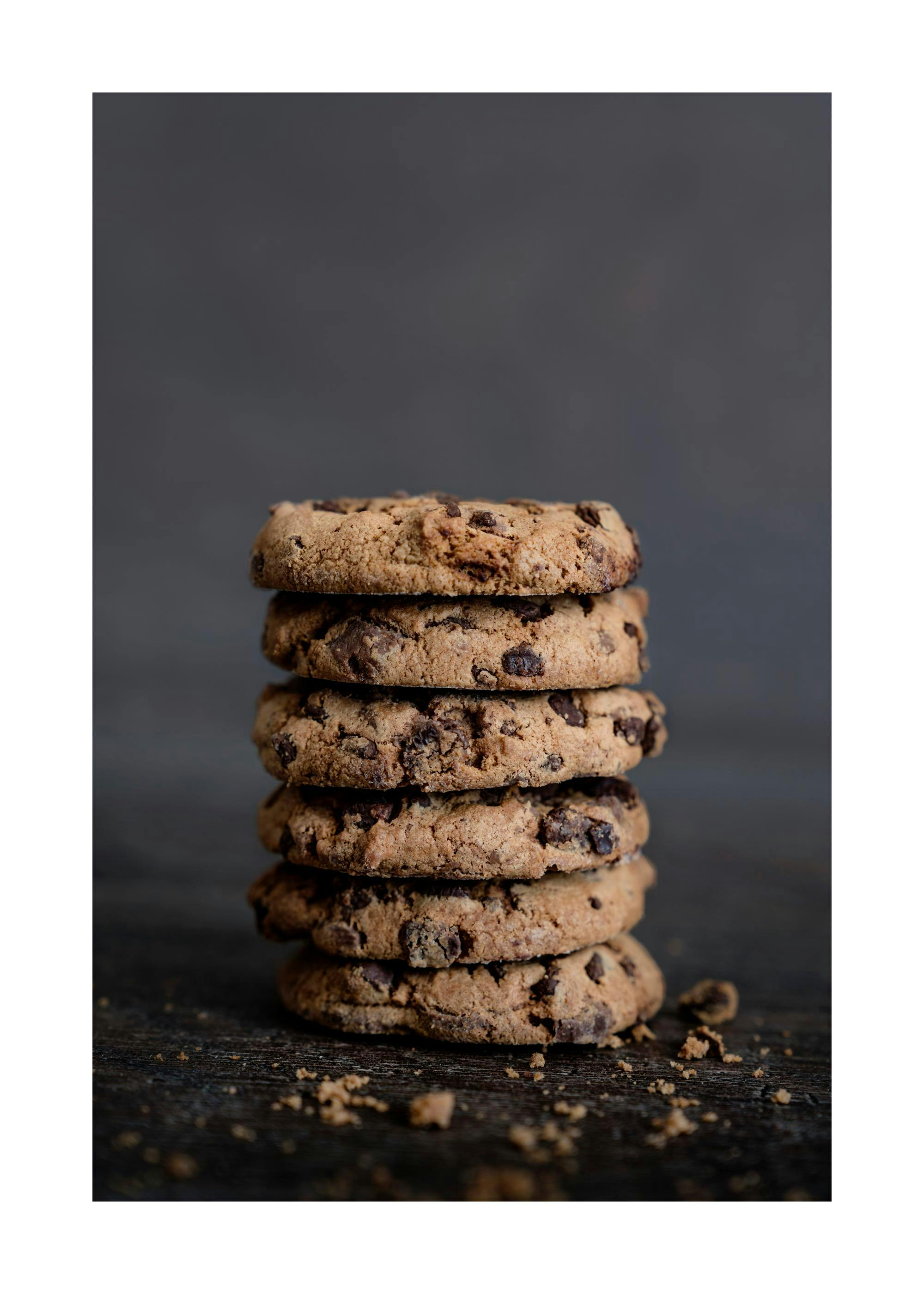 En poster som visar en stapel med chokladkakor på en mörk träyta med smulor.
