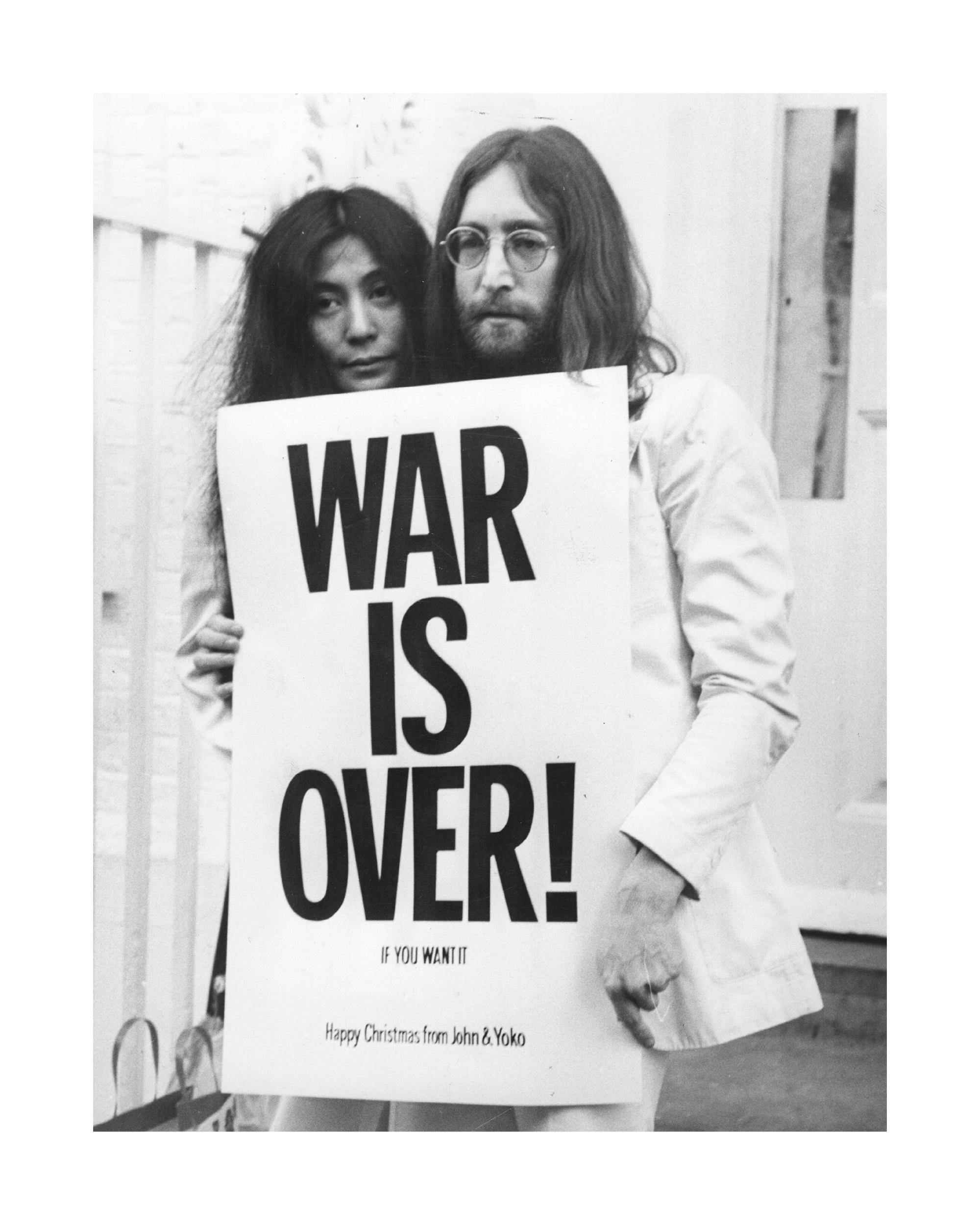 Plakát s ikonickou černobílou fotografií Johna Lennona a Yoko Ono držících nápis WAR IS OVER!