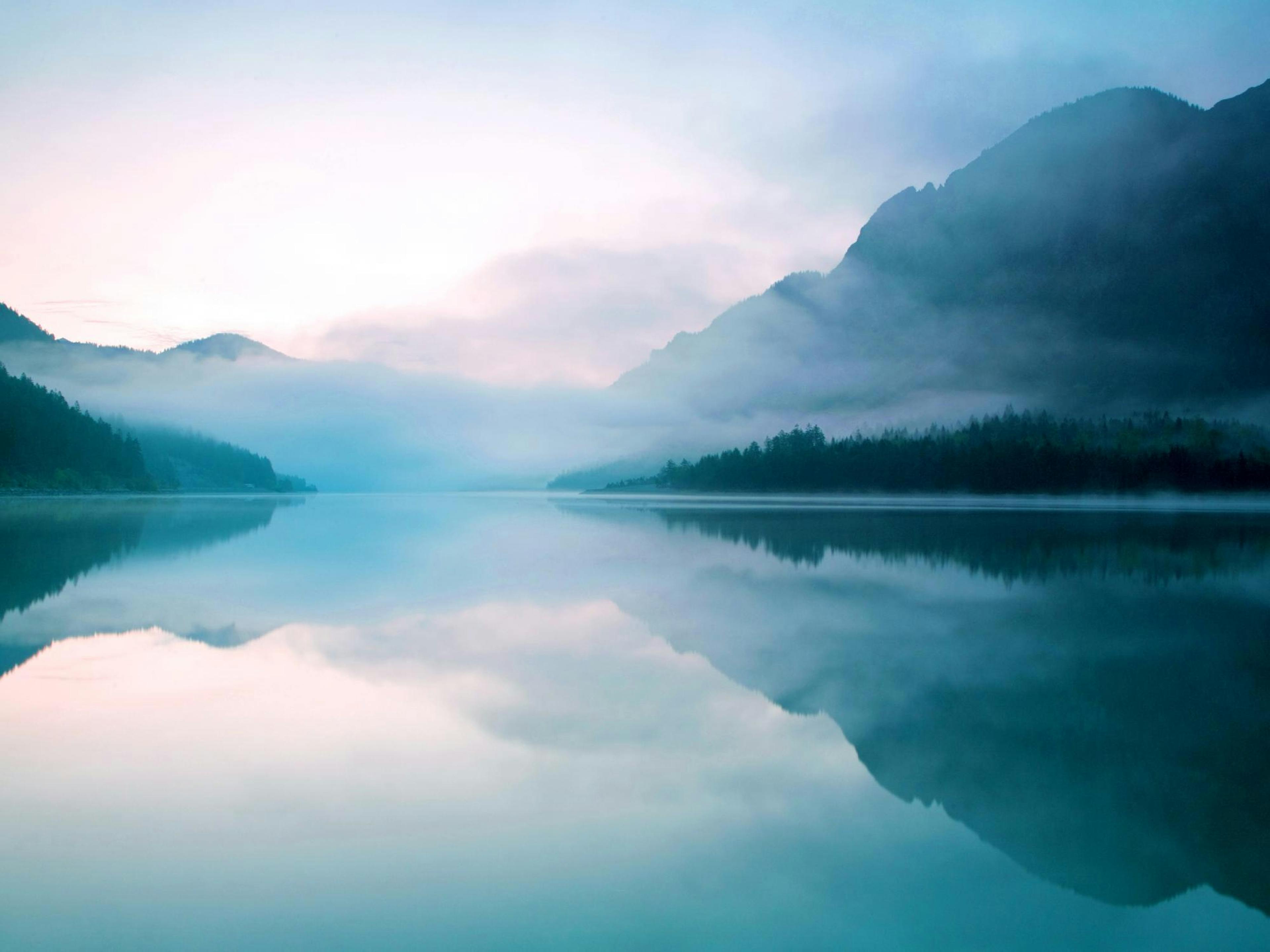 A poster depicting a serene lake reflecting misty mountains and a pale sky, with deep blue and soft pink hues.