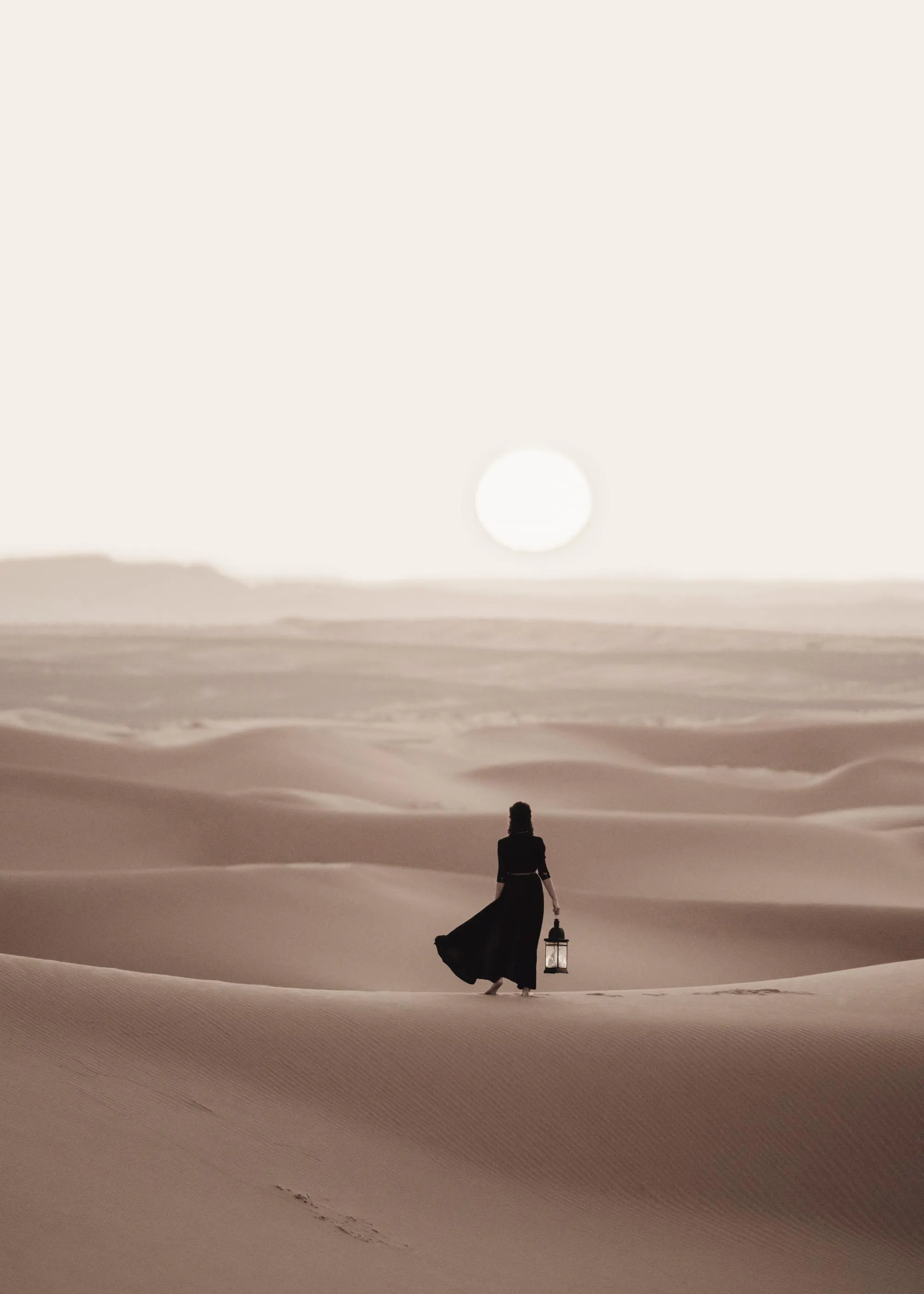 Póster de una figura femenina con una linterna, caminando en un desierto de dunas bajo un sol pálido.