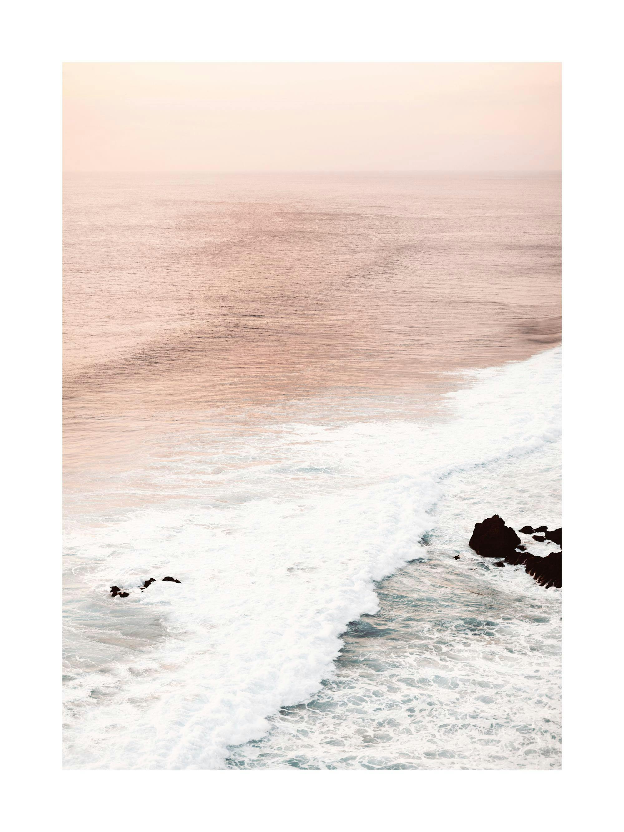 A poster featuring an aerial view of a pastel pink ocean with white waves crashing against dark rocks.