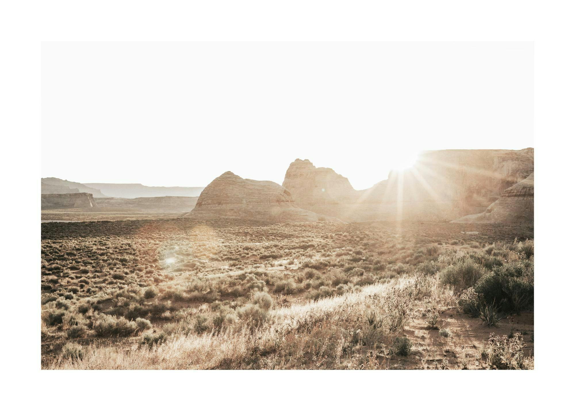 A poster featuring a desert landscape with large rock formations and bright sun rays across the sky.